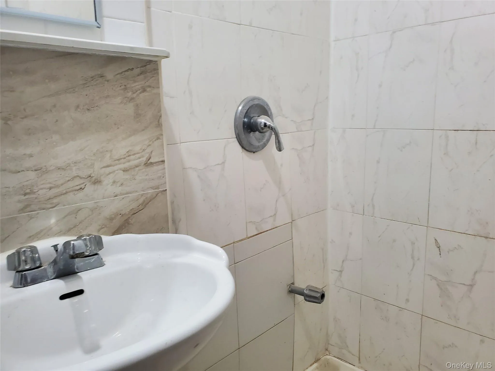 Bathroom featuring tiled shower and tile walls Bathroom featuring tiled shower and tile walls