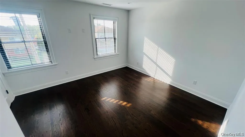Spare room with dark wood-style flooring and baseboards Spare room with dark wood-style flooring and baseboards