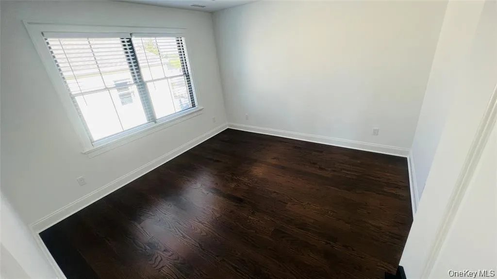 Empty room featuring dark wood-style floors and baseboards Empty room featuring dark wood-style floors and baseboards
