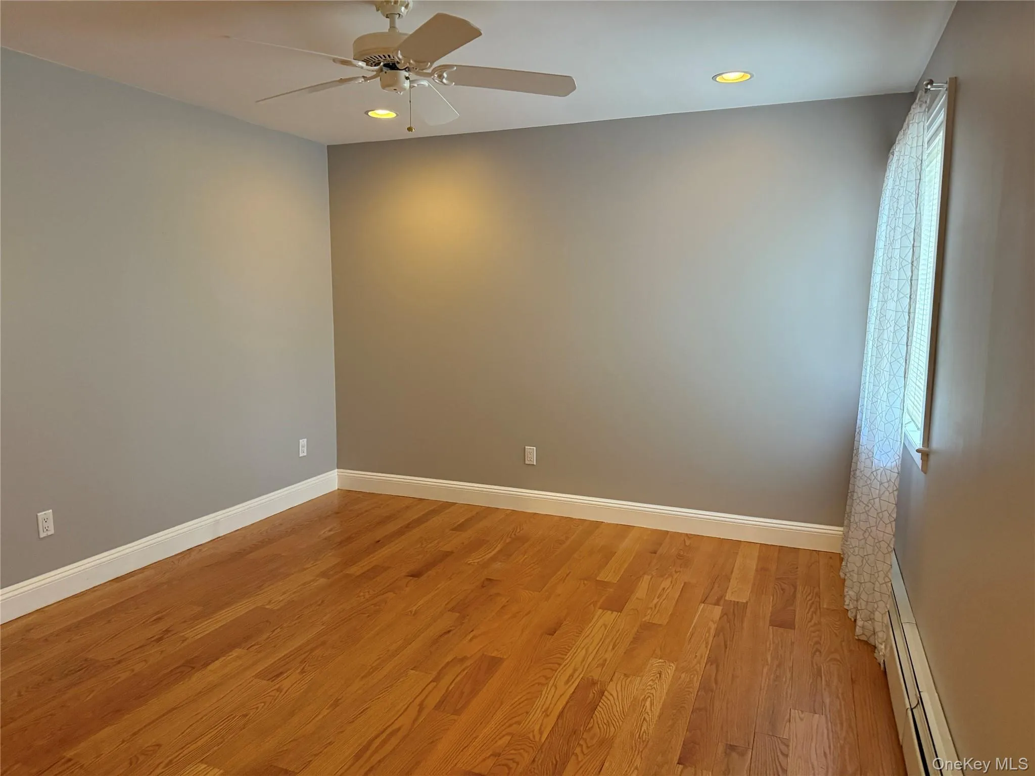 Unfurnished room with light wood-type flooring, a baseboard radiator, ceiling fan, and recessed lighting Unfurnished room with light wood-type flooring, a baseboard radiator, ceiling fan, and recessed lighting