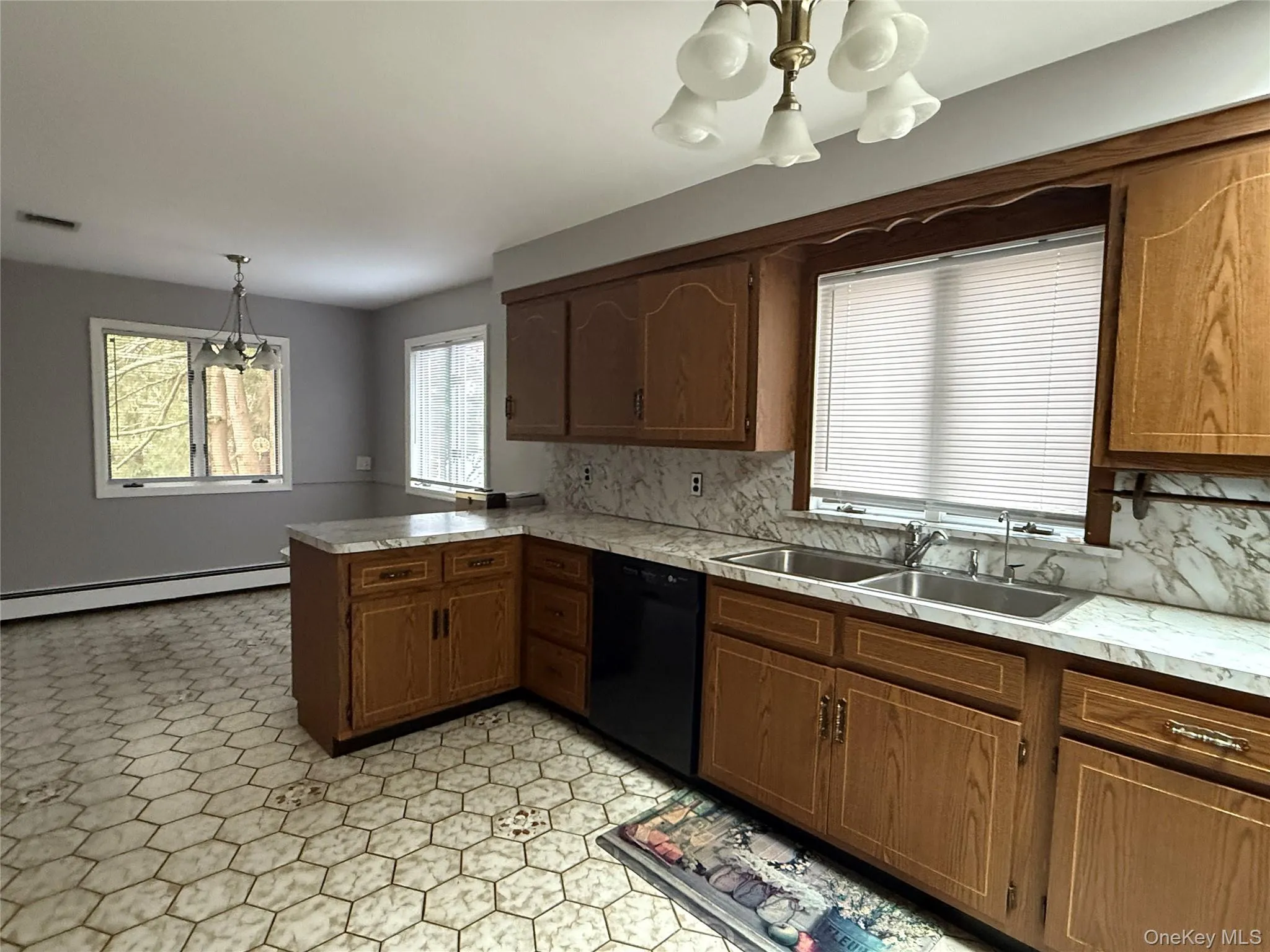 Kitchen with hanging light fixtures, light countertops, a peninsula, tasteful backsplash, and dishwasher Kitchen with hanging light fixtures, light countertops, a peninsula, tasteful backsplash, and dishwasher