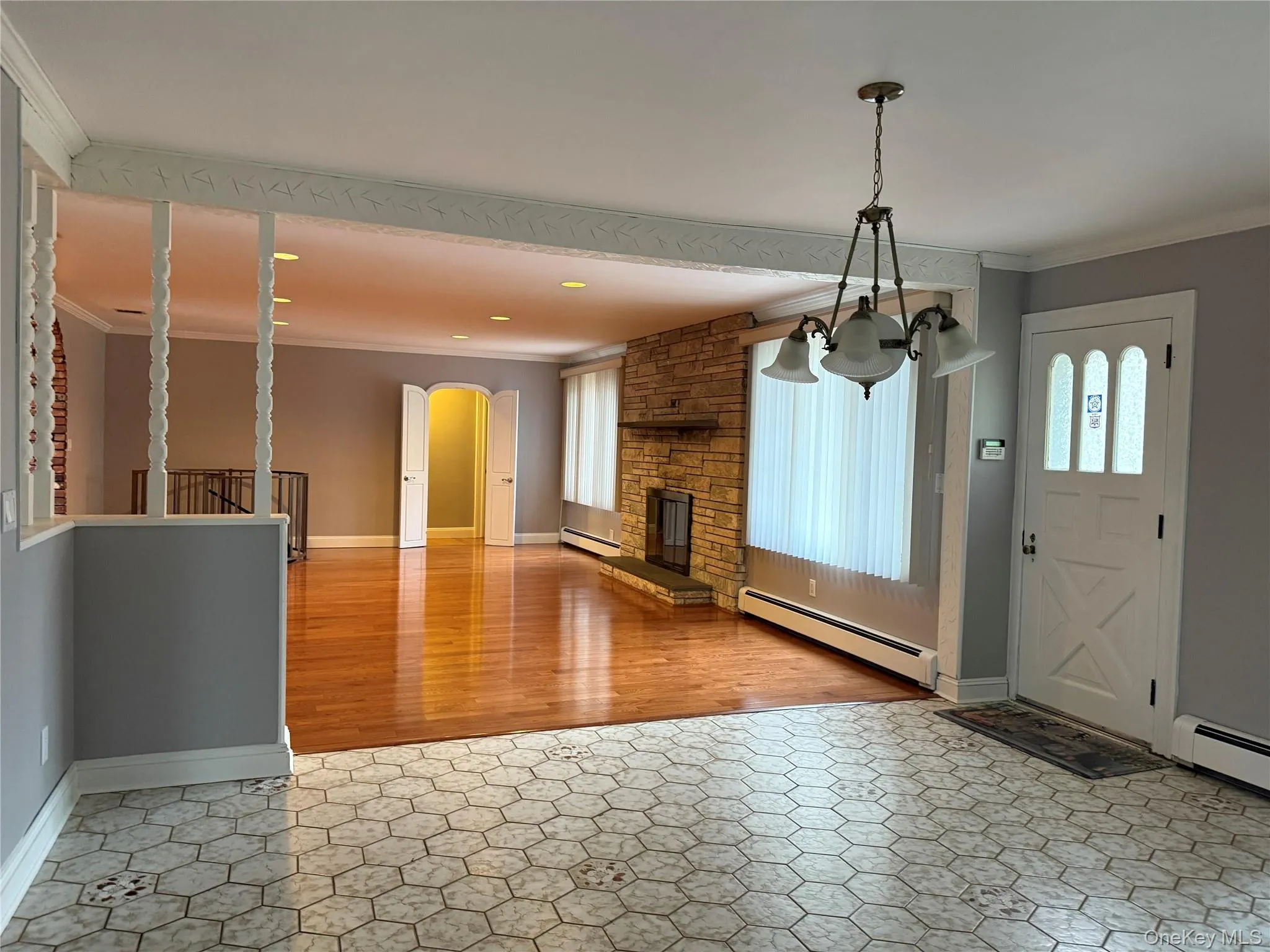 Entrance foyer featuring ornamental molding, a baseboard heating unit, arched walkways, plenty of natural light, and light wood finished floors Entrance foyer featuring ornamental molding, a baseboard heating unit, arched walkways, plenty of natural light, and light wood finished floors