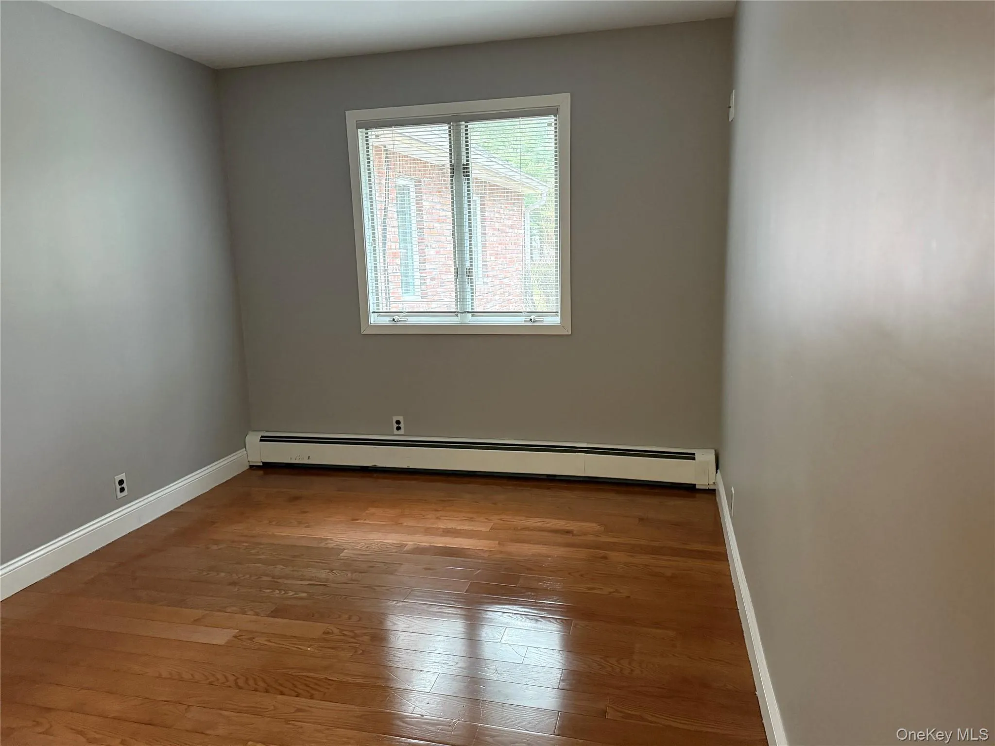 Spare room featuring a baseboard heating unit and light wood finished floors Spare room featuring a baseboard heating unit and light wood finished floors