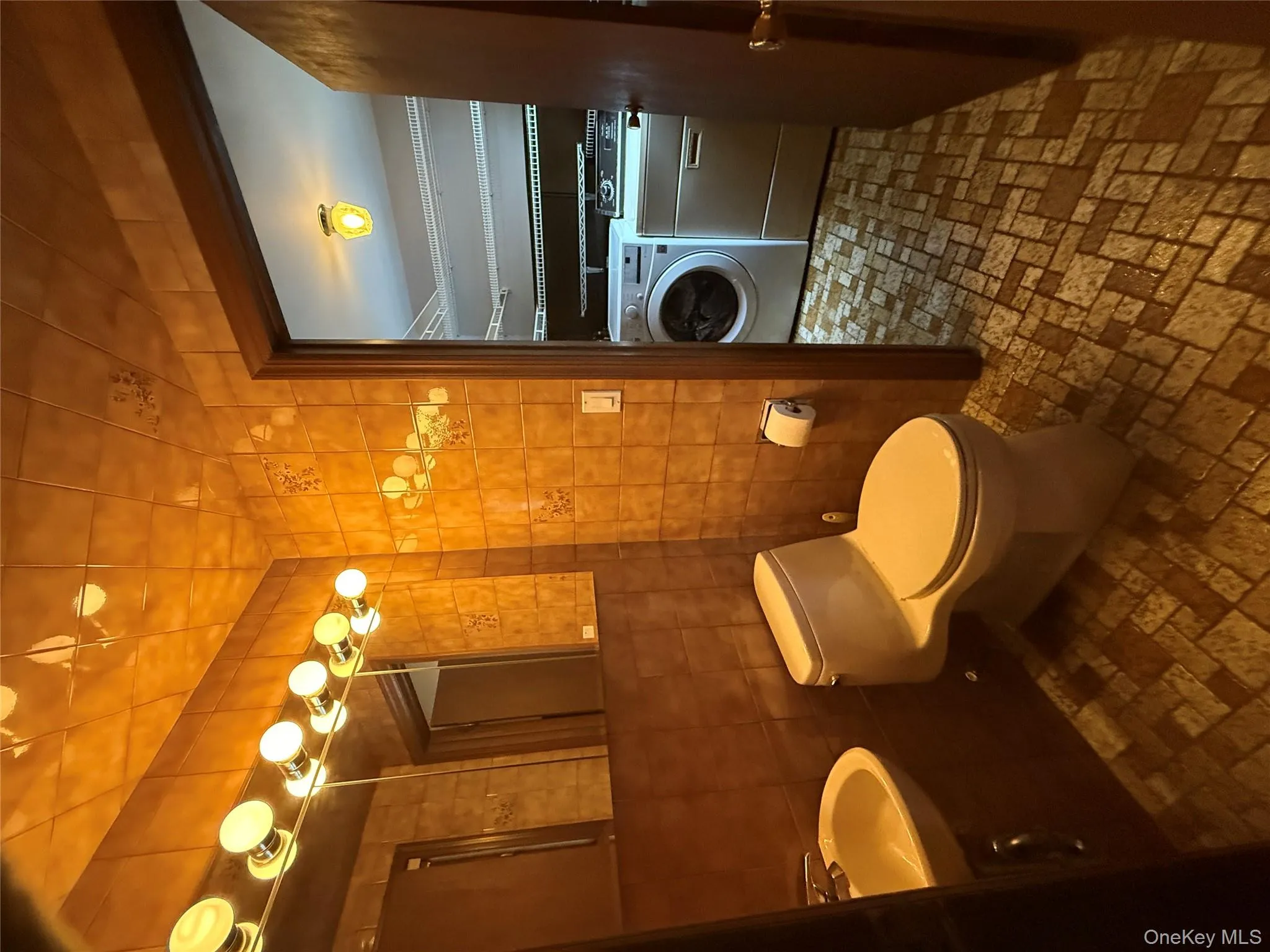 Bathroom featuring washer and clothes dryer, brick patterned floors, and tile walls Bathroom featuring washer and clothes dryer, brick patterned floors, and tile walls