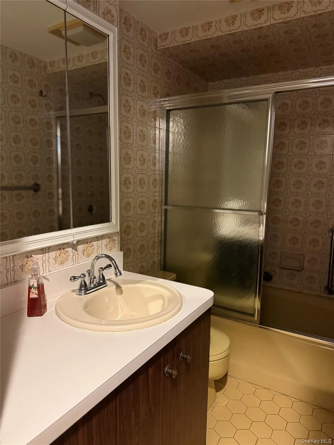 Full bathroom with vanity, combined bath / shower with glass door, and light tile patterned floors Full bathroom with vanity, combined bath / shower with glass door, and light tile patterned floors