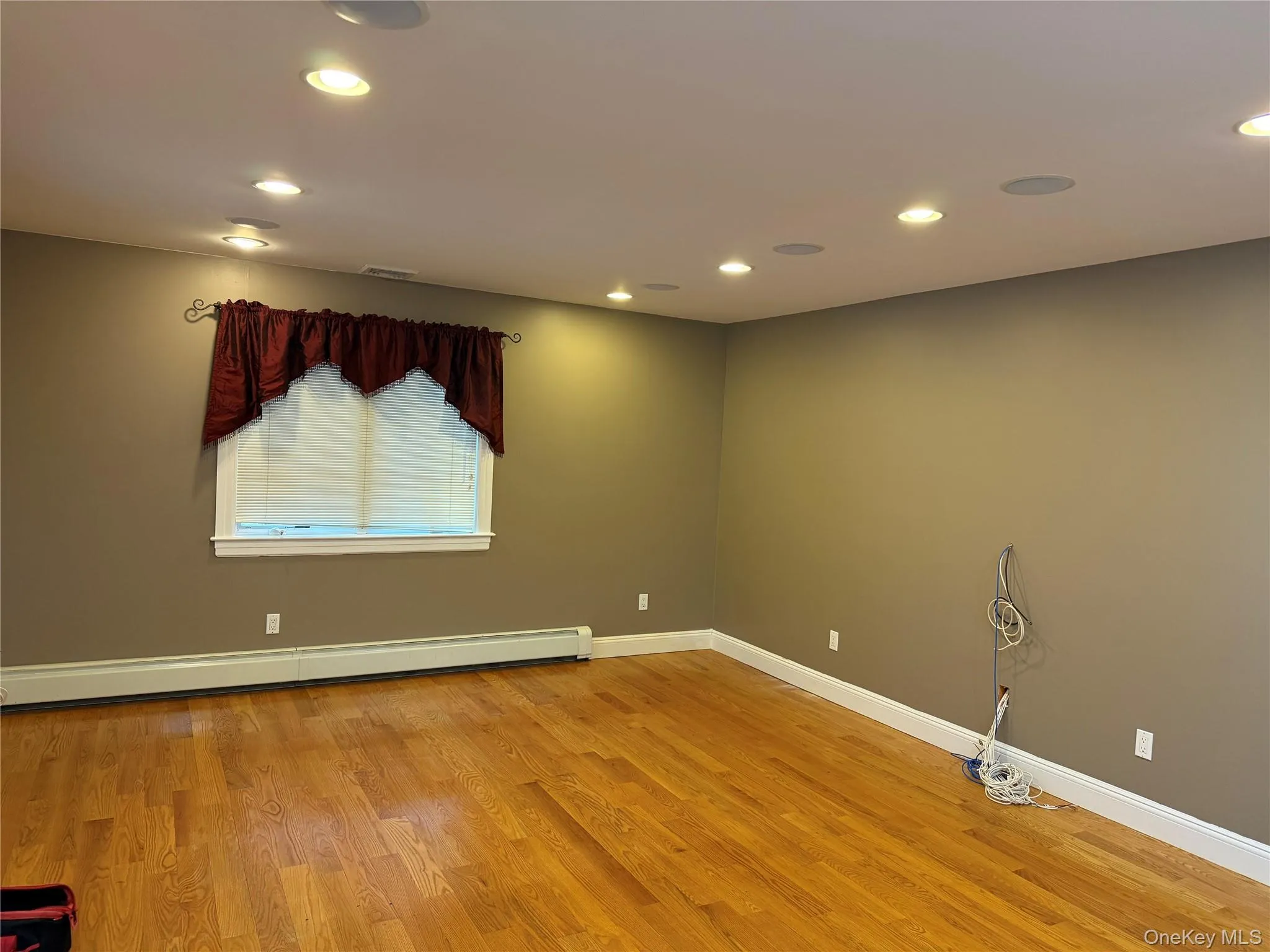 Empty room featuring light wood-style floors, a baseboard heating unit, and recessed lighting Empty room featuring light wood-style floors, a baseboard heating unit, and recessed lighting