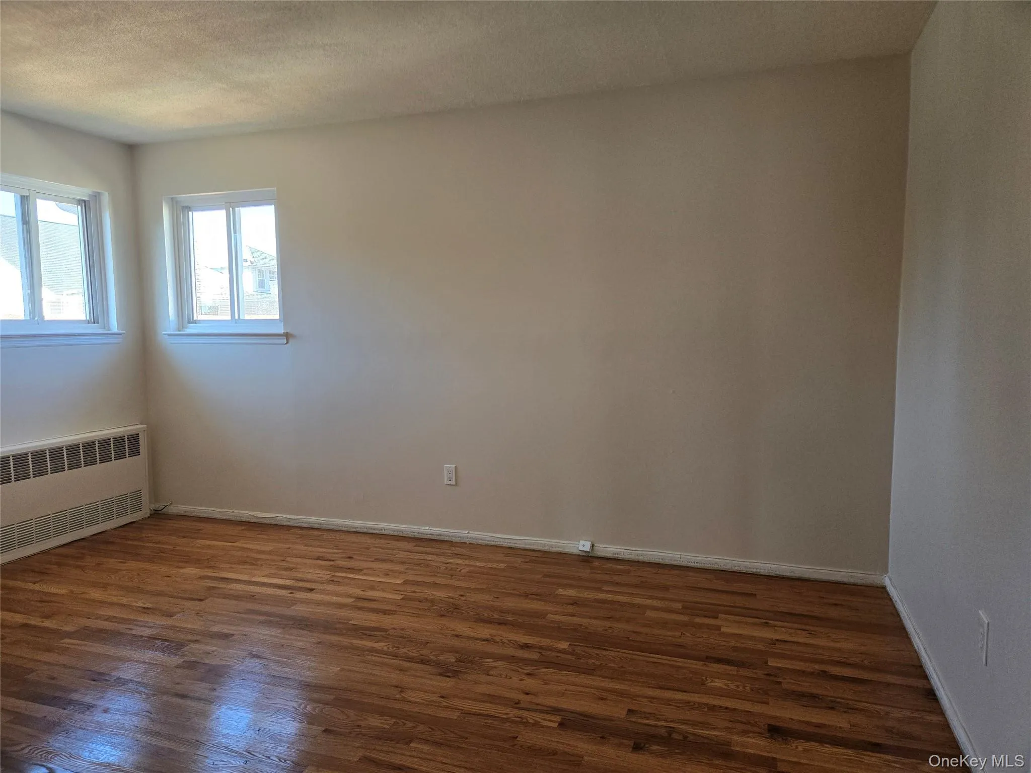 Spare room featuring dark wood-style floors, radiator, and a textured ceiling Spare room featuring dark wood-style floors, radiator, and a textured ceiling