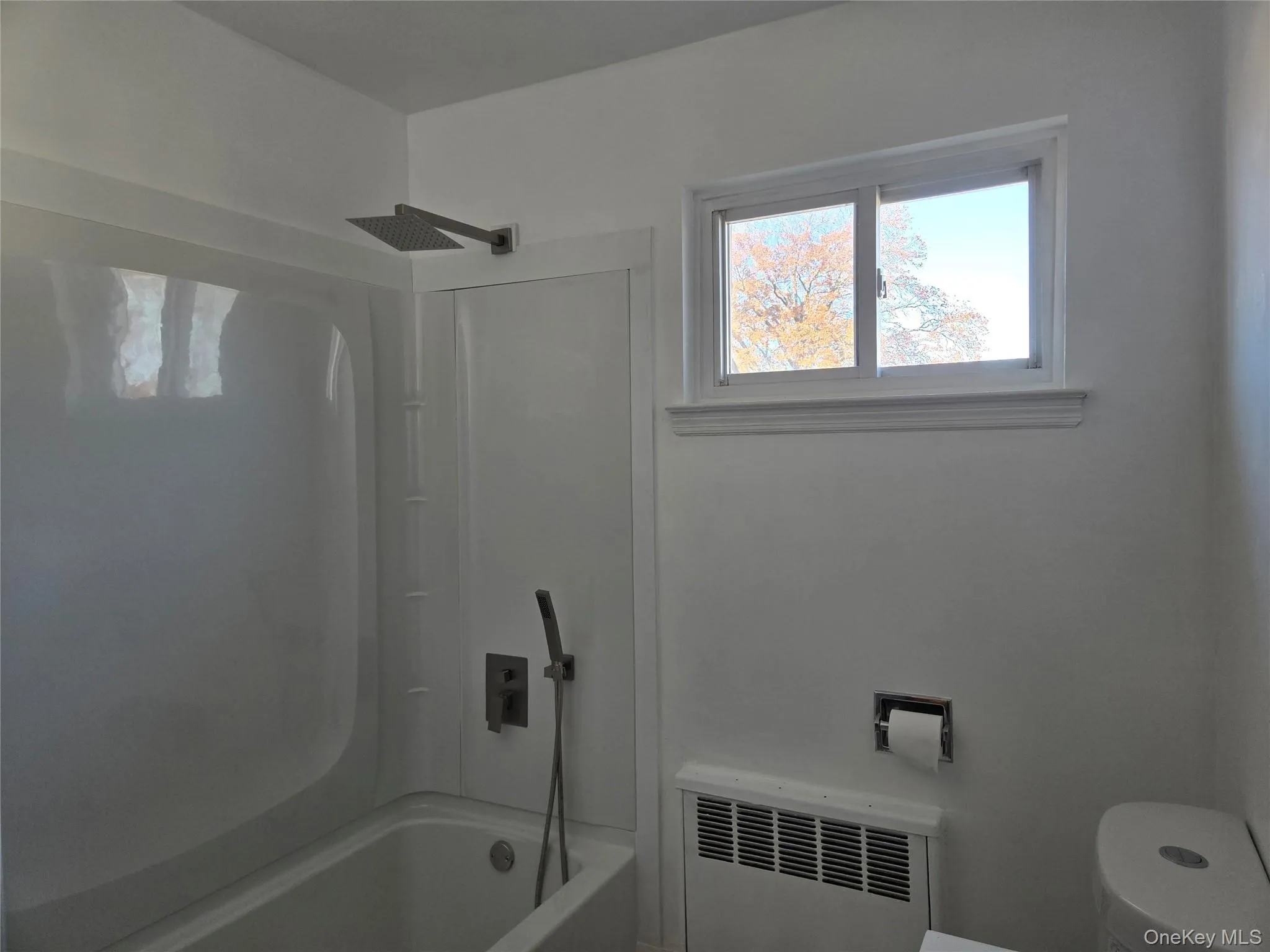 Full bath with radiator heating unit, healthy amount of natural light, and shower combination Full bath with radiator heating unit, healthy amount of natural light, and shower combination