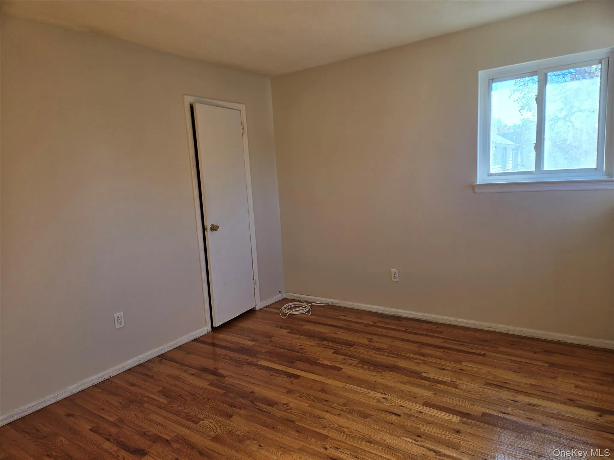 Unfurnished room with dark wood-style flooring and baseboards Unfurnished room with dark wood-style flooring and baseboards