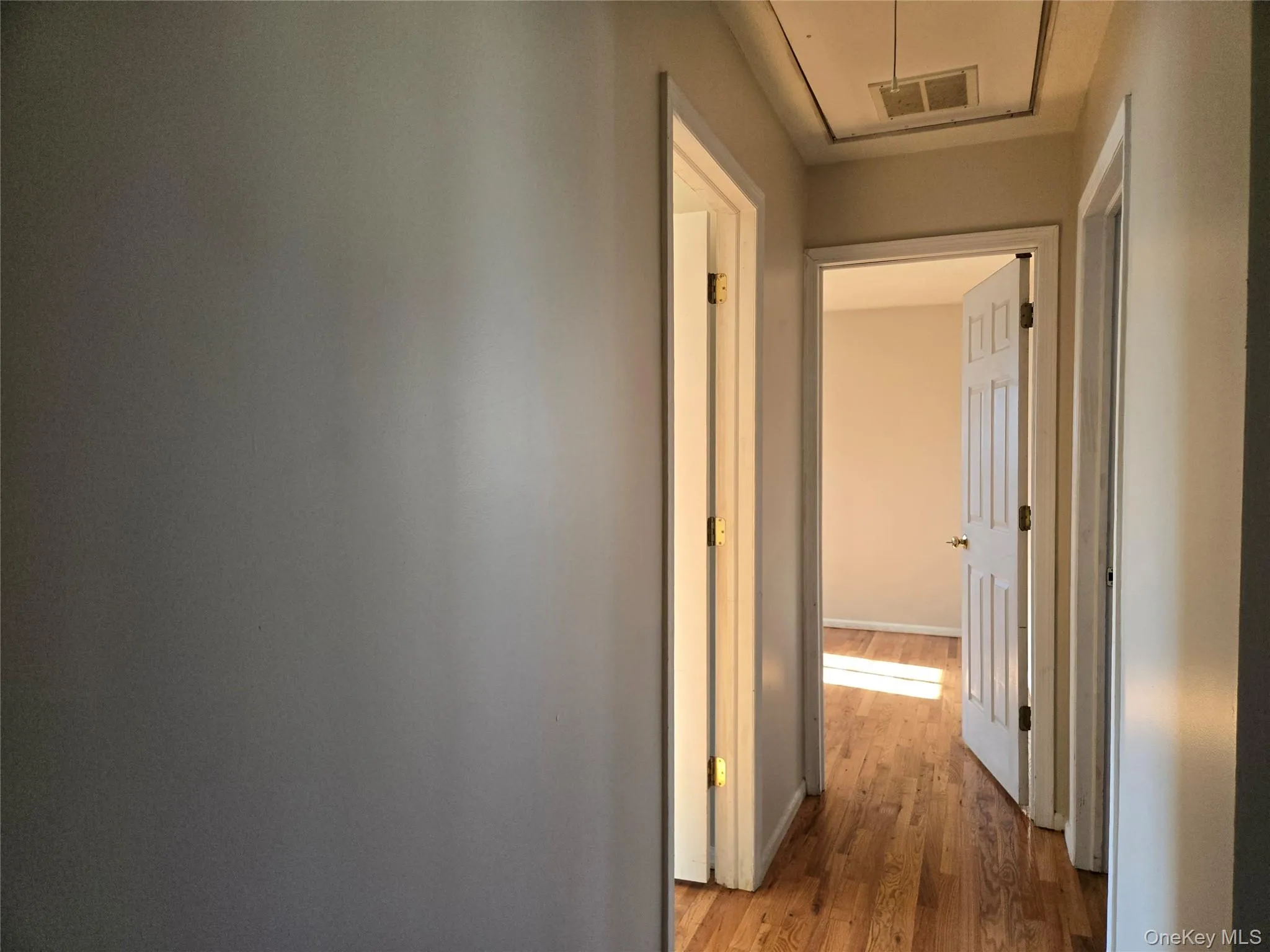 Hallway with attic access and hardwood / wood-style flooring Hallway with attic access and hardwood / wood-style flooring