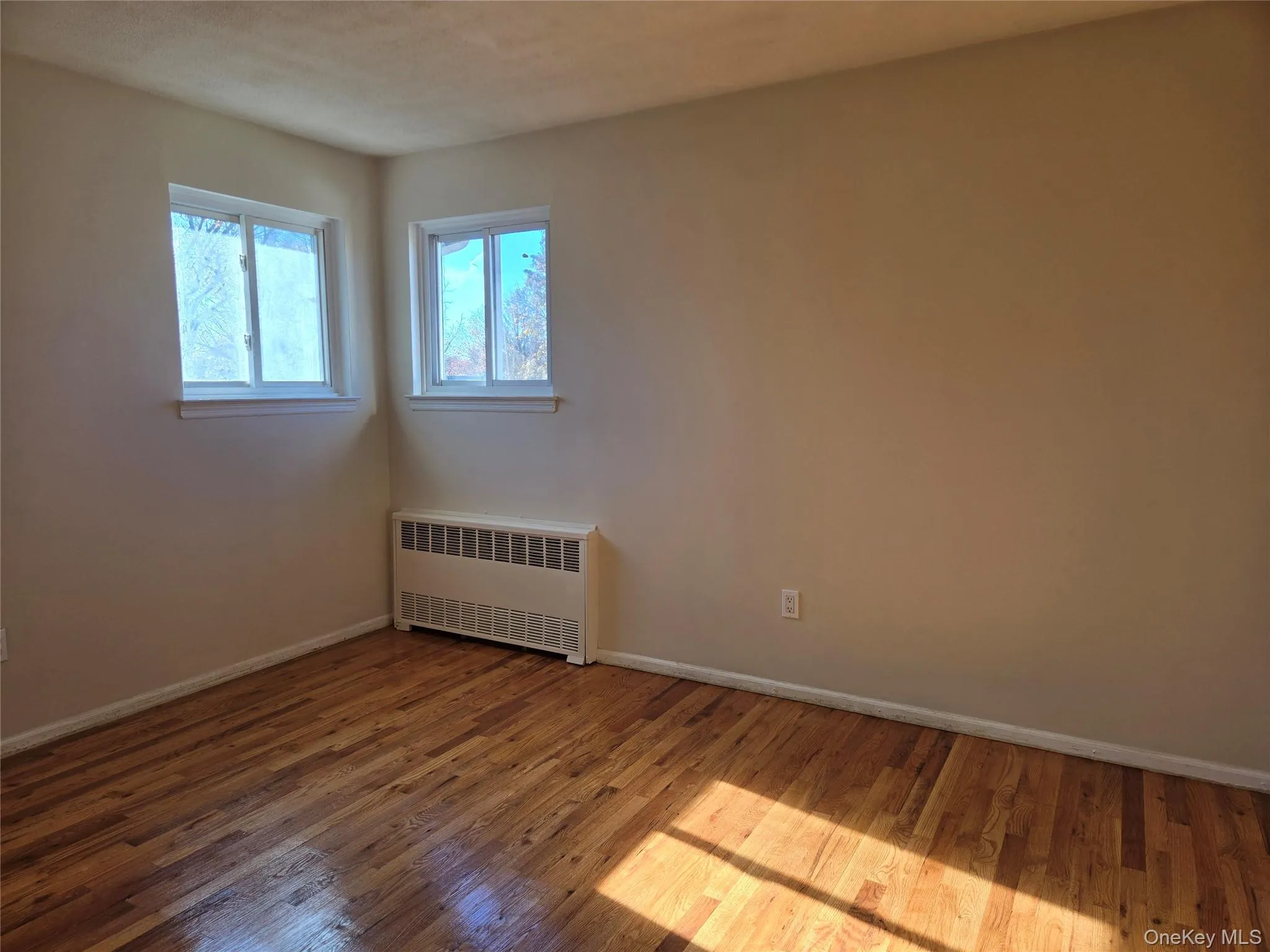 Spare room featuring radiator heating unit and wood-type flooring Spare room featuring radiator heating unit and wood-type flooring