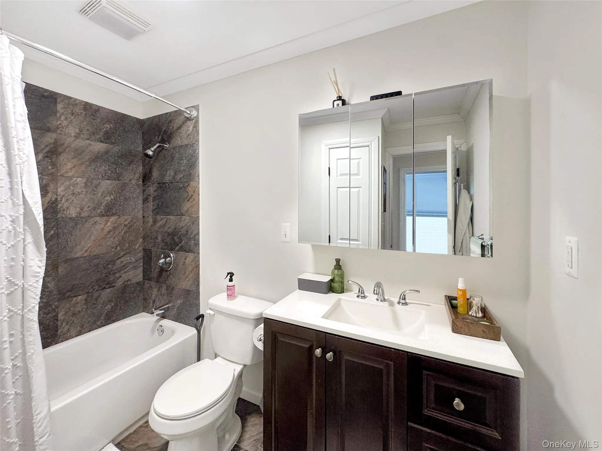 Full bathroom featuring shower / bath combination with curtain, vanity, and ornamental molding Full bathroom featuring shower / bath combination with curtain, vanity, and ornamental molding