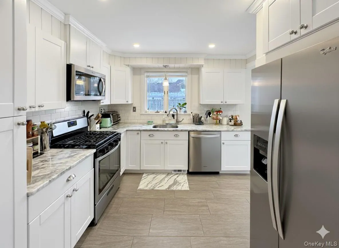 Kitchen with stainless steel appliances, light stone counters, white cabinetry, recessed lighting, and crown molding Kitchen with stainless steel appliances, light stone counters, white cabinetry, recessed lighting, and crown molding
