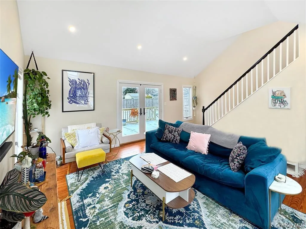 Living area featuring french doors, lofted ceiling, wood finished floors, and stairs Living area featuring french doors, lofted ceiling, wood finished floors, and stairs