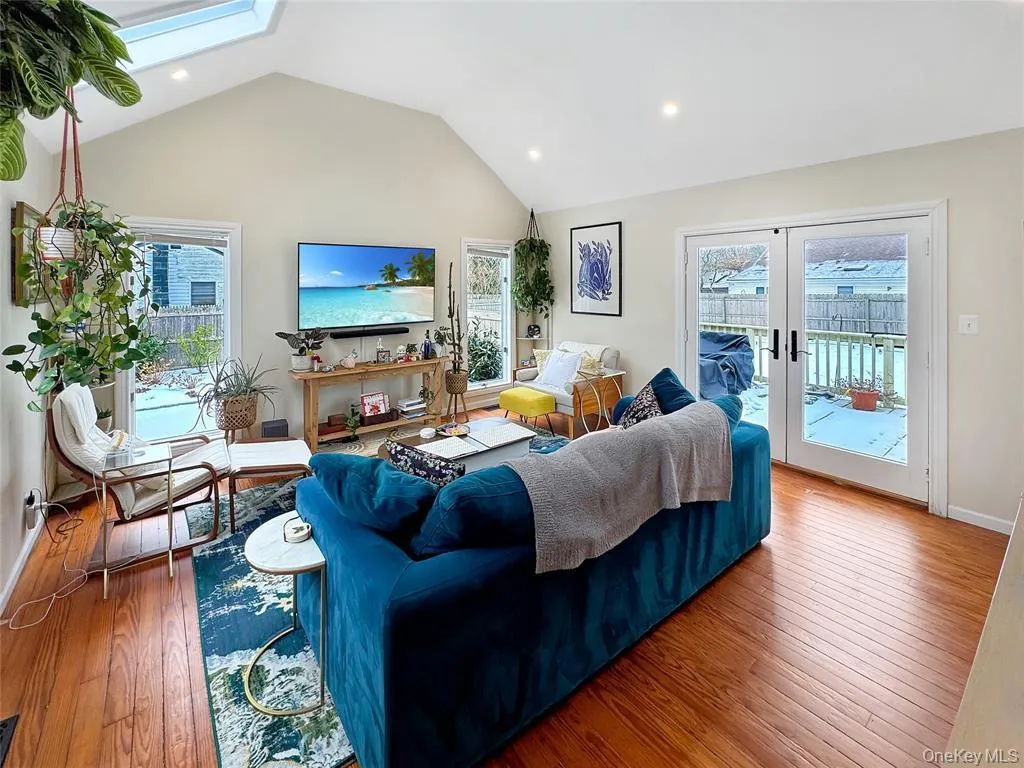 Living room featuring vaulted ceiling, a skylight, healthy amount of natural light, recessed lighting, and wood-type flooring Living room featuring vaulted ceiling, a skylight, healthy amount of natural light, recessed lighting, and wood-type flooring
