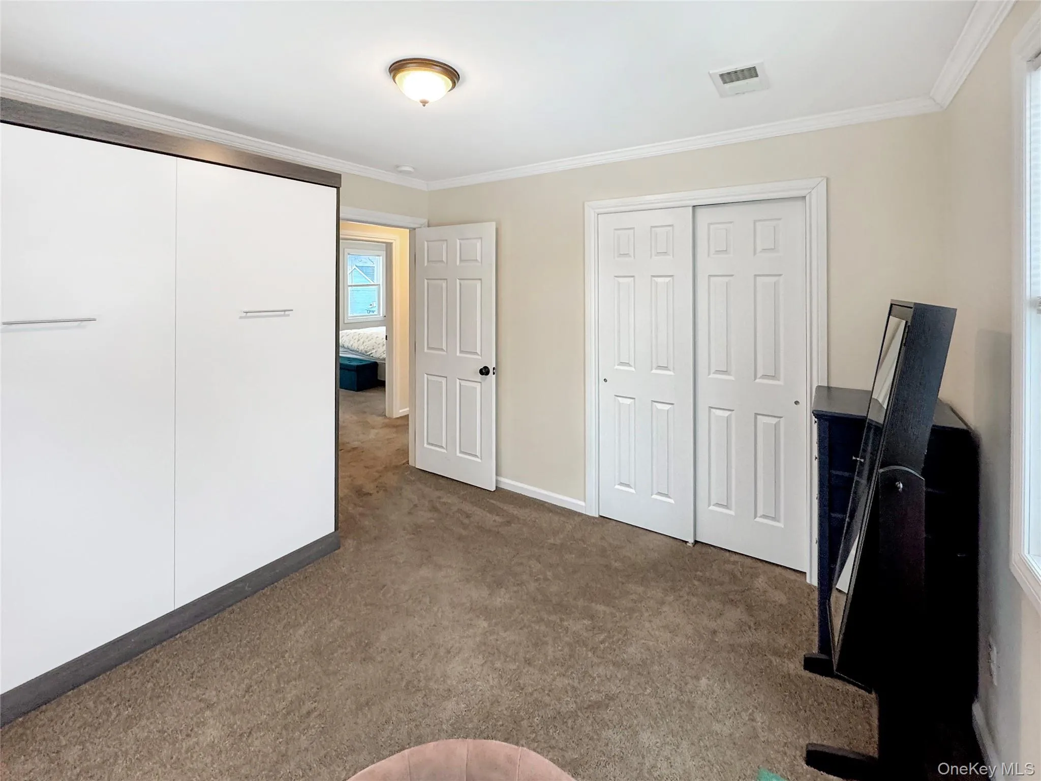 Unfurnished bedroom featuring dark colored carpet and ornamental molding Unfurnished bedroom featuring dark colored carpet and ornamental molding