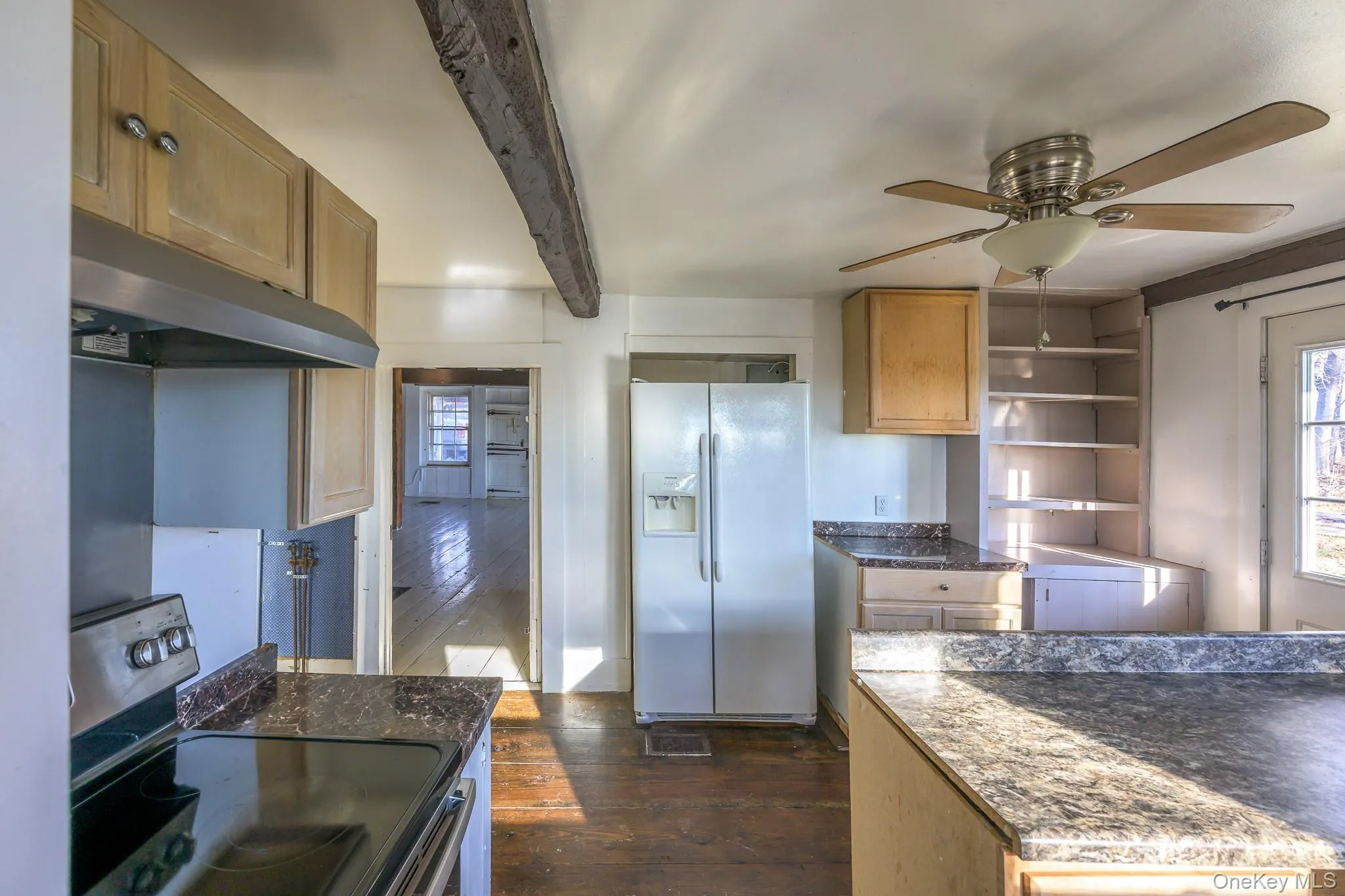 Kitchen featuring electric range, dark wood-style floors, white fridge with ice dispenser, under cabinet range hood, and dark countertops Kitchen featuring electric range, dark wood-style floors, white fridge with ice dispenser, under cabinet range hood, and dark countertops