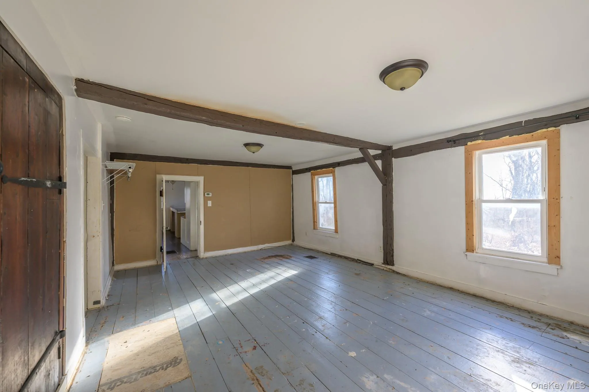 Empty room featuring hardwood / wood-style floors and beam ceiling Empty room featuring hardwood / wood-style floors and beam ceiling
