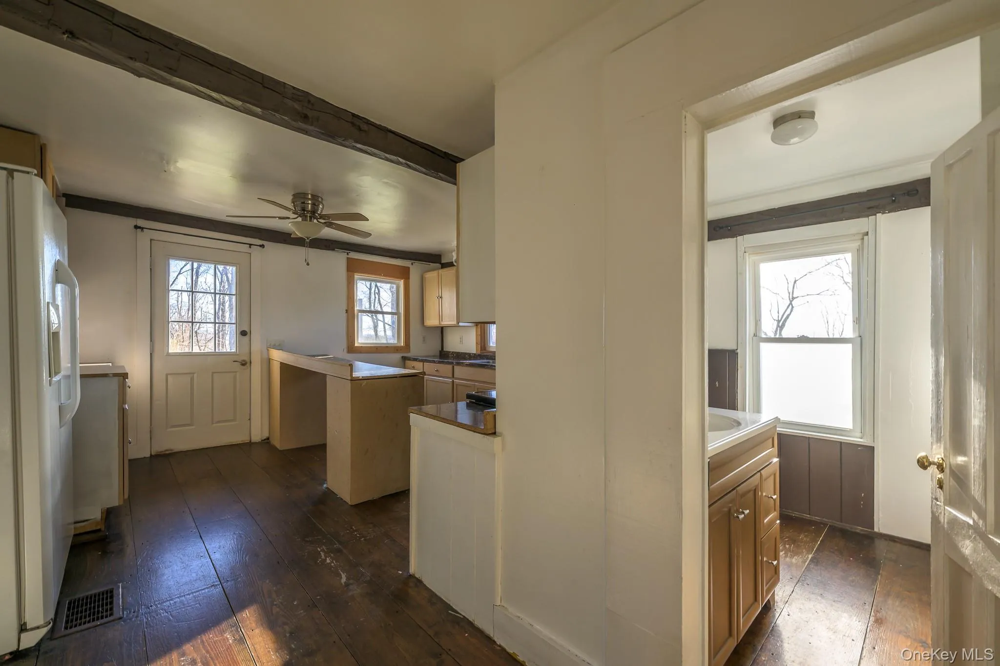 Kitchen featuring white refrigerator with ice dispenser, dark wood-style flooring, a ceiling fan, and beam ceiling Kitchen featuring white refrigerator with ice dispenser, dark wood-style flooring, a ceiling fan, and beam ceiling