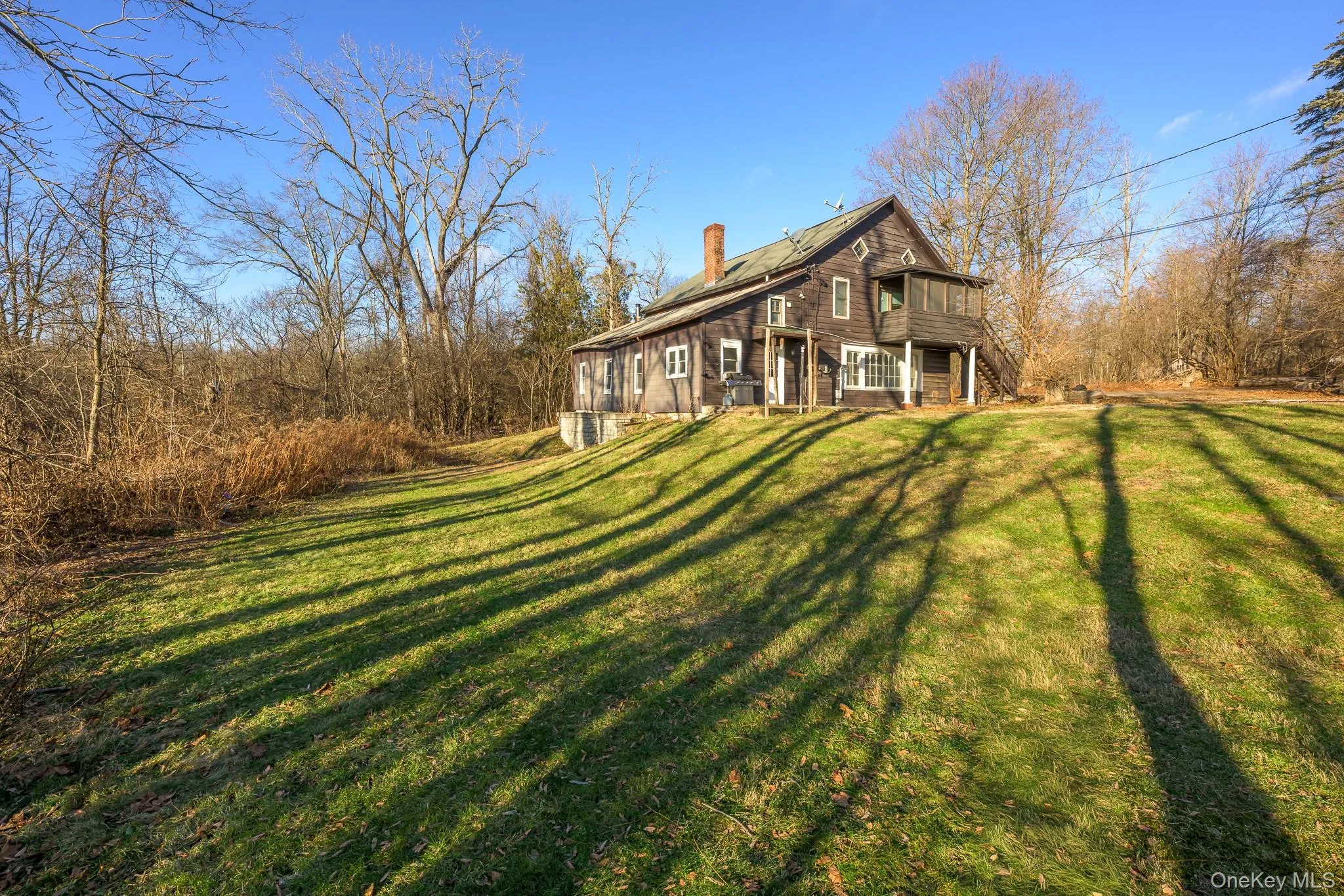 View of home's exterior with roof mounted solar panels, a chimney, a lawn, stairway, and a wooden deck View of home's exterior with roof mounted solar panels, a chimney, a lawn, stairway, and a wooden deck