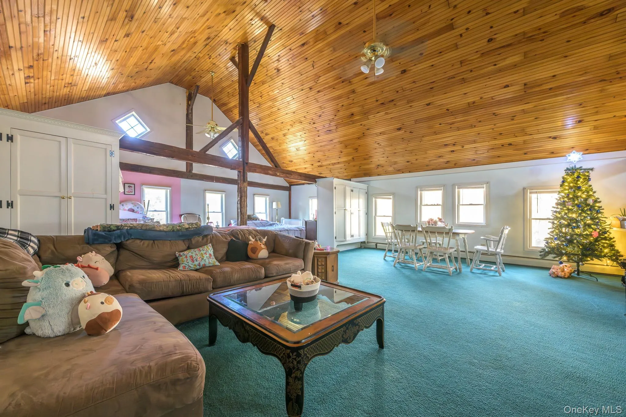 Carpeted living room featuring plenty of natural light, wood ceiling, high vaulted ceiling, and a ceiling fan Carpeted living room featuring plenty of natural light, wood ceiling, high vaulted ceiling, and a ceiling fan