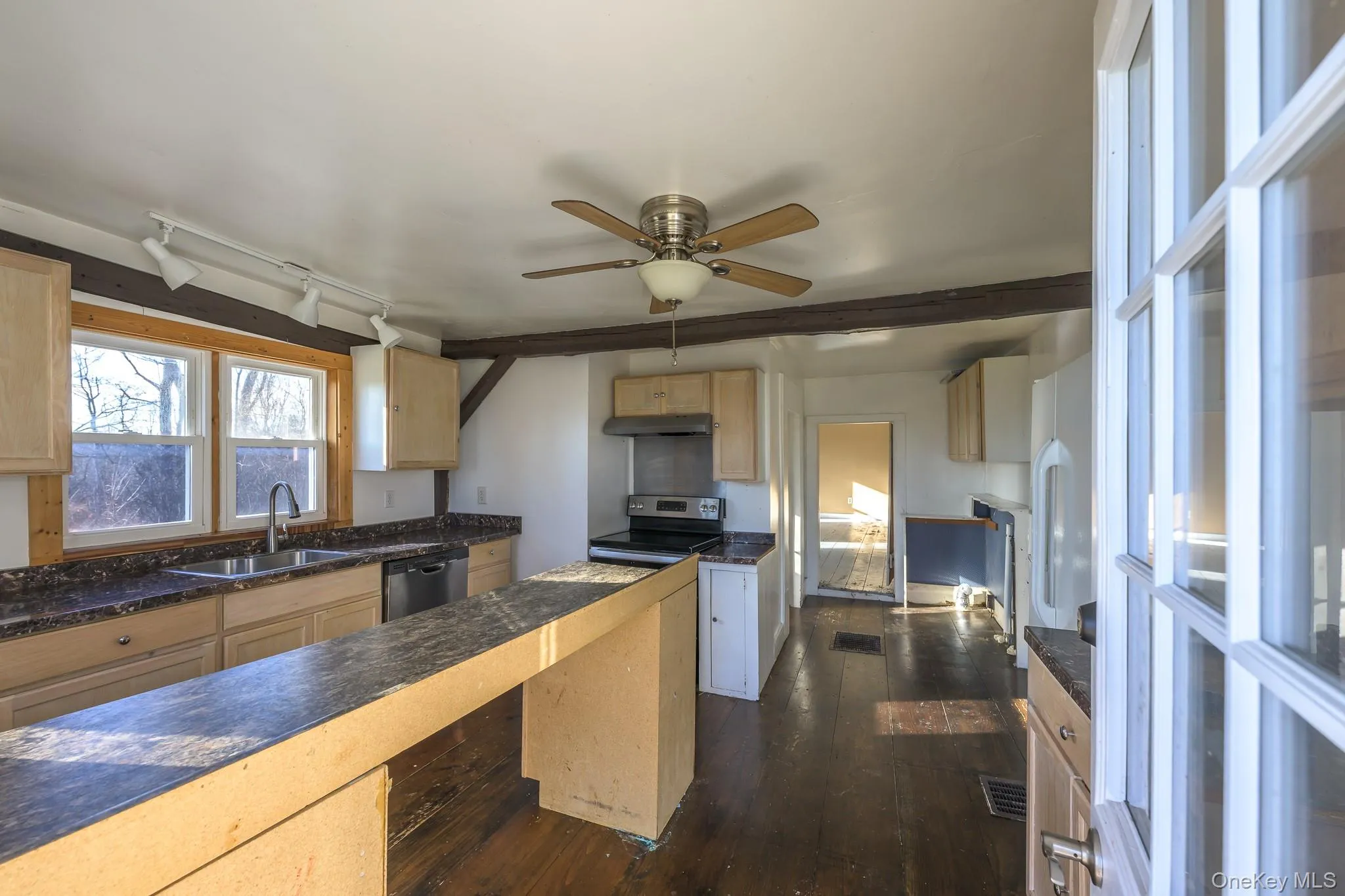 Kitchen with light brown cabinetry, track lighting, appliances with stainless steel finishes, dark wood-style flooring, and ceiling fan Kitchen with light brown cabinetry, track lighting, appliances with stainless steel finishes, dark wood-style flooring, and ceiling fan
