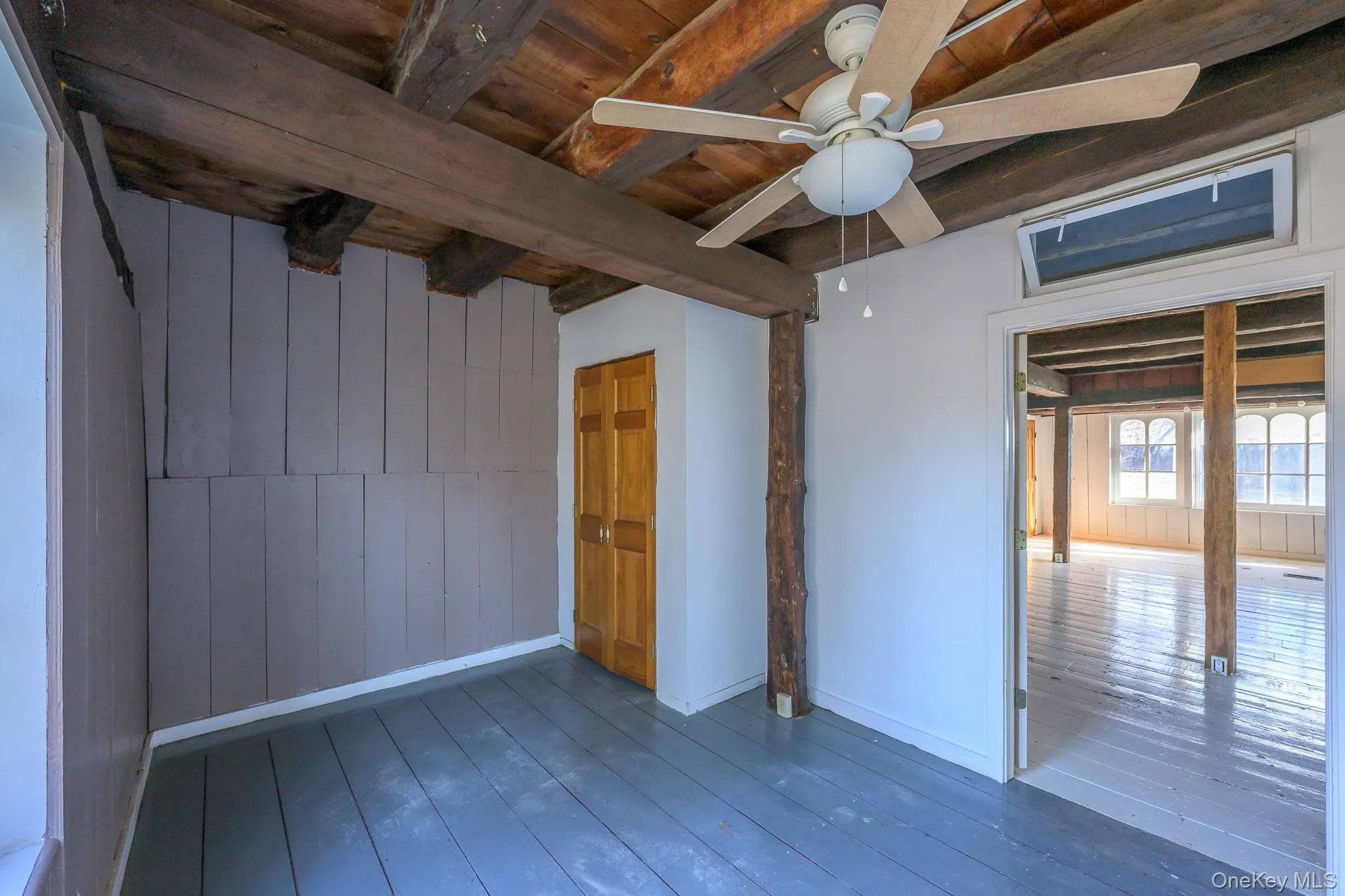 Spare room with wooden walls, a wooden ceiling with exposed beams, hardwood / wood-style floors, and ceiling fan Spare room with wooden walls, a wooden ceiling with exposed beams, hardwood / wood-style floors, and ceiling fan