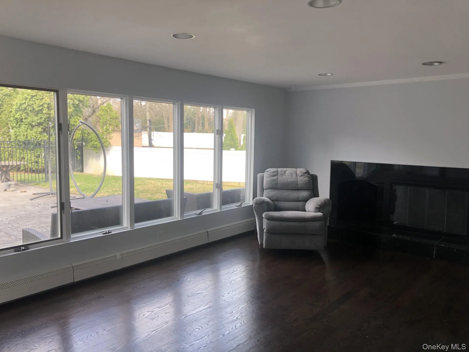 Sitting room with ornamental molding, dark wood-style floors, a glass covered fireplace, and recessed lighting Sitting room with ornamental molding, dark wood-style floors, a glass covered fireplace, and recessed lighting