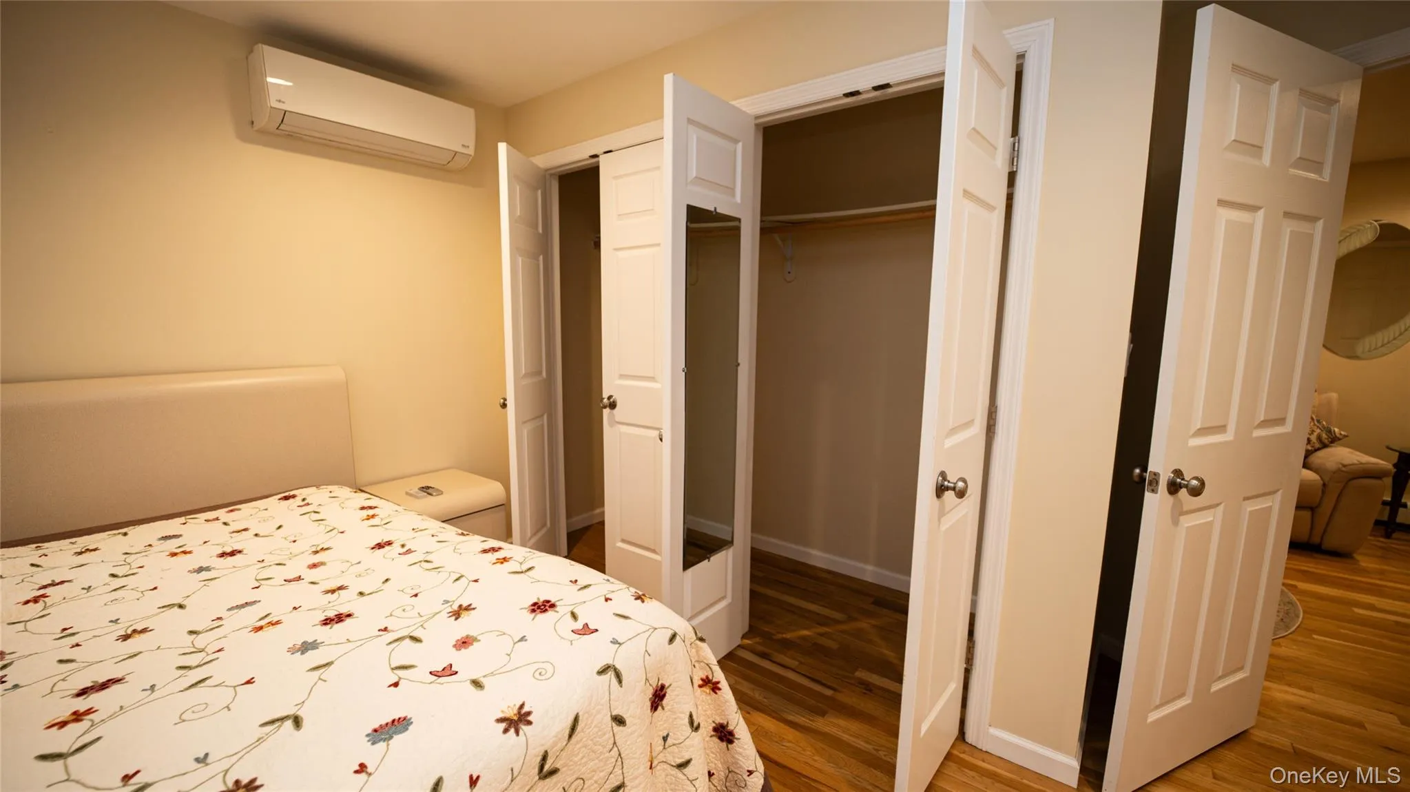 Bedroom featuring a wall mounted AC, light wood-style flooring, and a closet Bedroom featuring a wall mounted AC, light wood-style flooring, and a closet