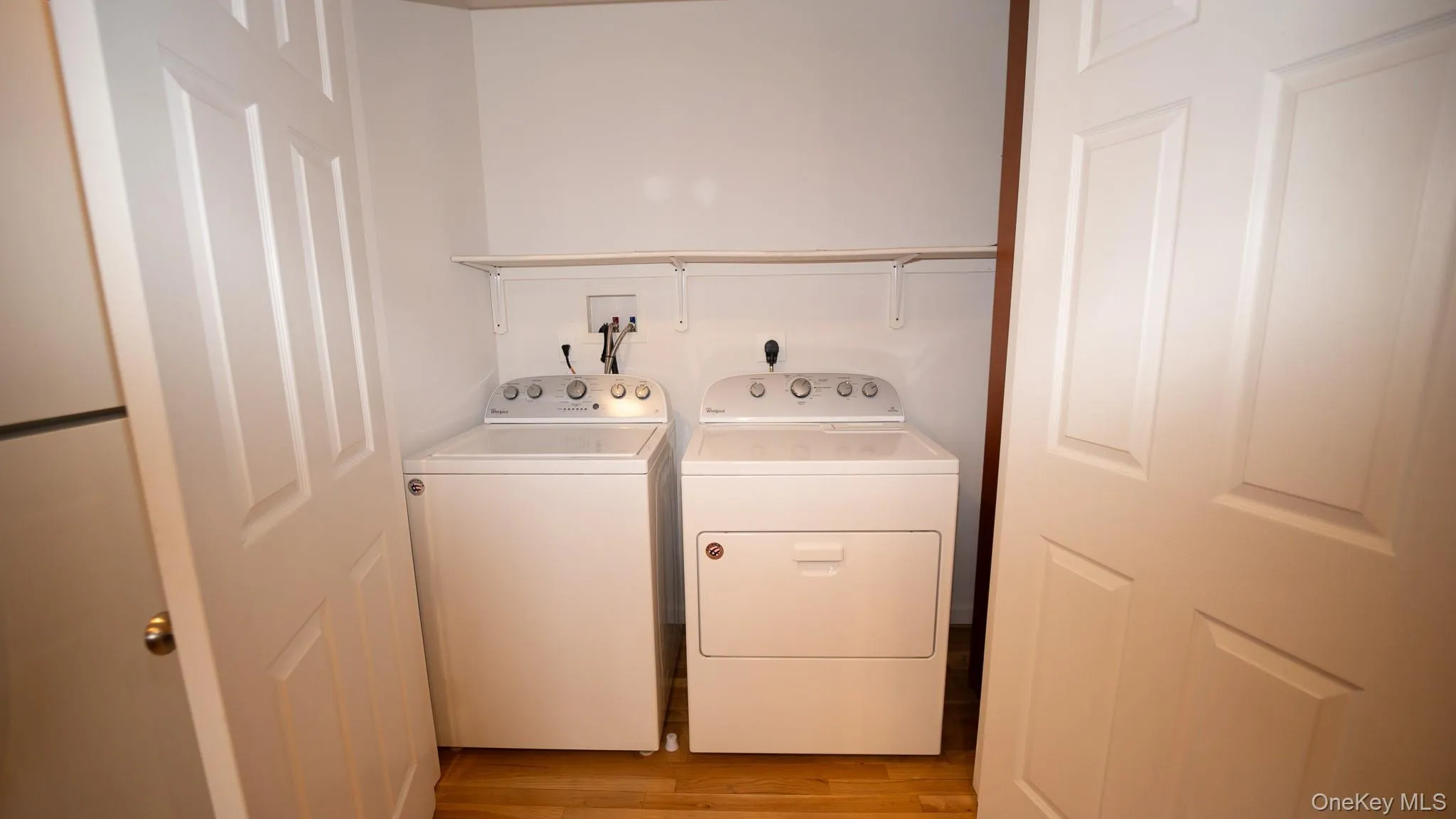 Laundry room featuring washing machine and dryer and light wood-type flooring Laundry room featuring washing machine and dryer and light wood-type flooring