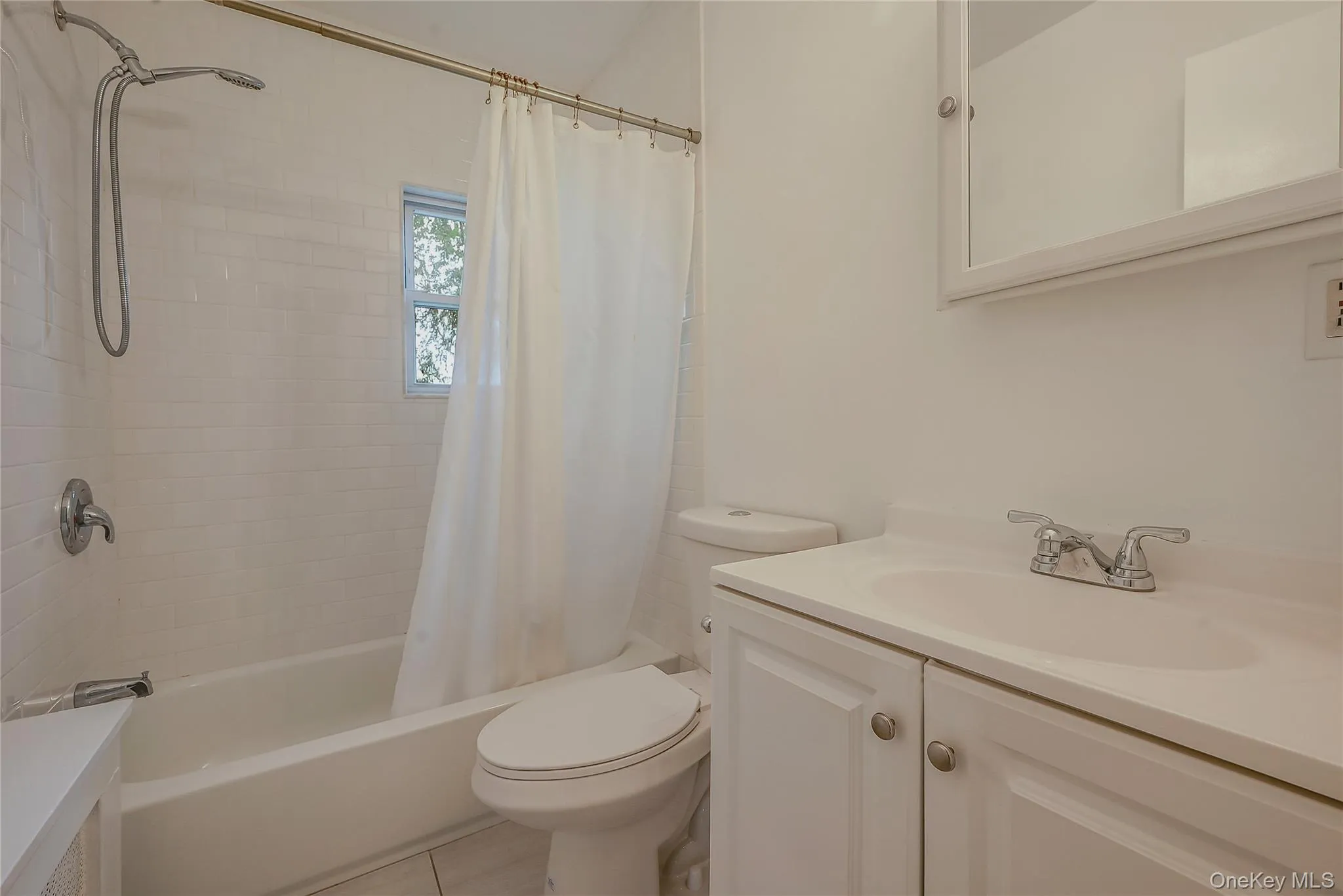 Full bath featuring vanity, shower / tub combo, and light tile patterned floors Full bath featuring vanity, shower / tub combo, and light tile patterned floors