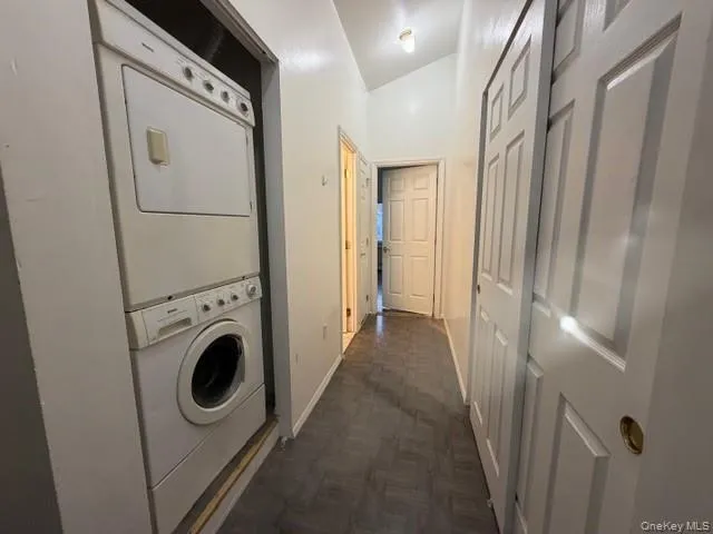 Laundry area featuring stacked washing machine and dryer and lofted ceiling Laundry area featuring stacked washing machine and dryer and lofted ceiling