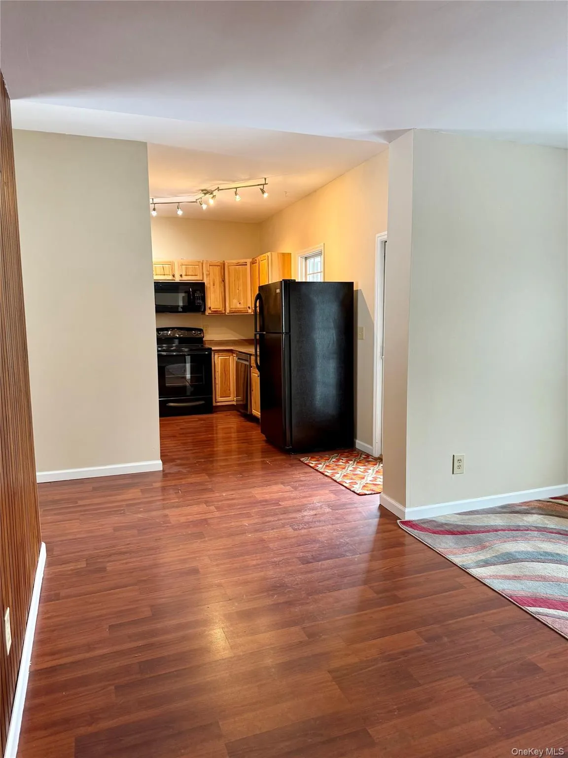 Kitchen featuring black appliances, dark wood-style flooring, and open floor plan Kitchen featuring black appliances, dark wood-style flooring, and open floor plan