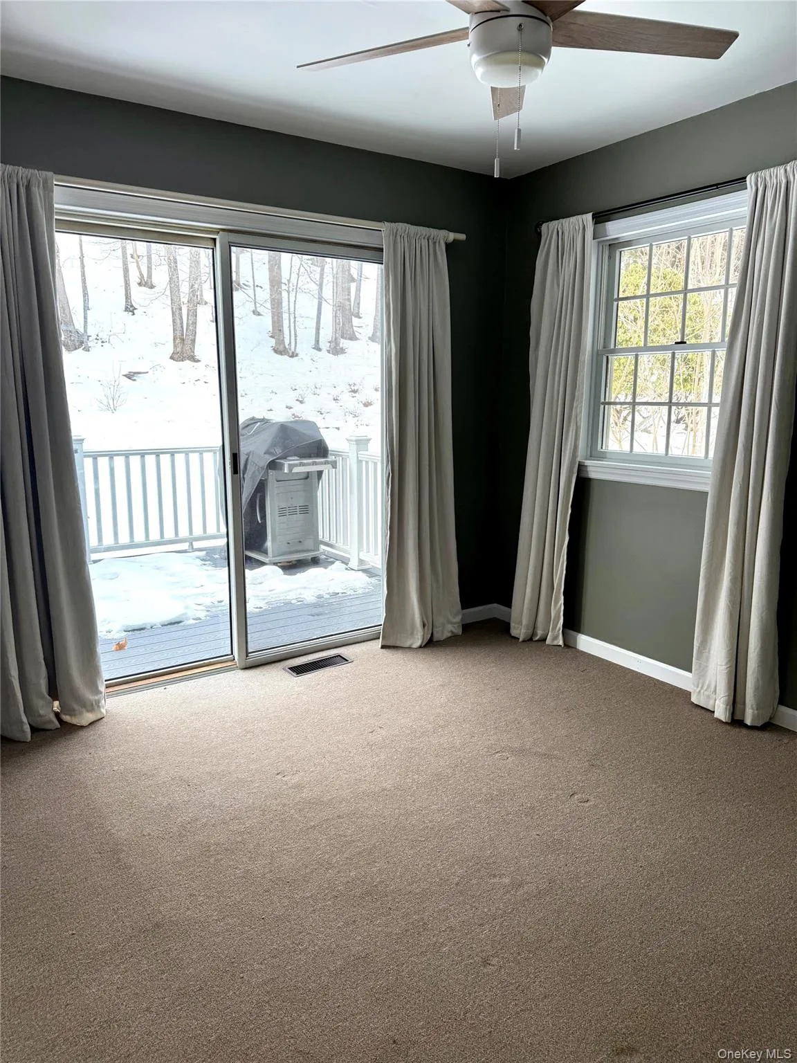 Carpeted empty room with a ceiling fan and baseboards Carpeted empty room with a ceiling fan and baseboards