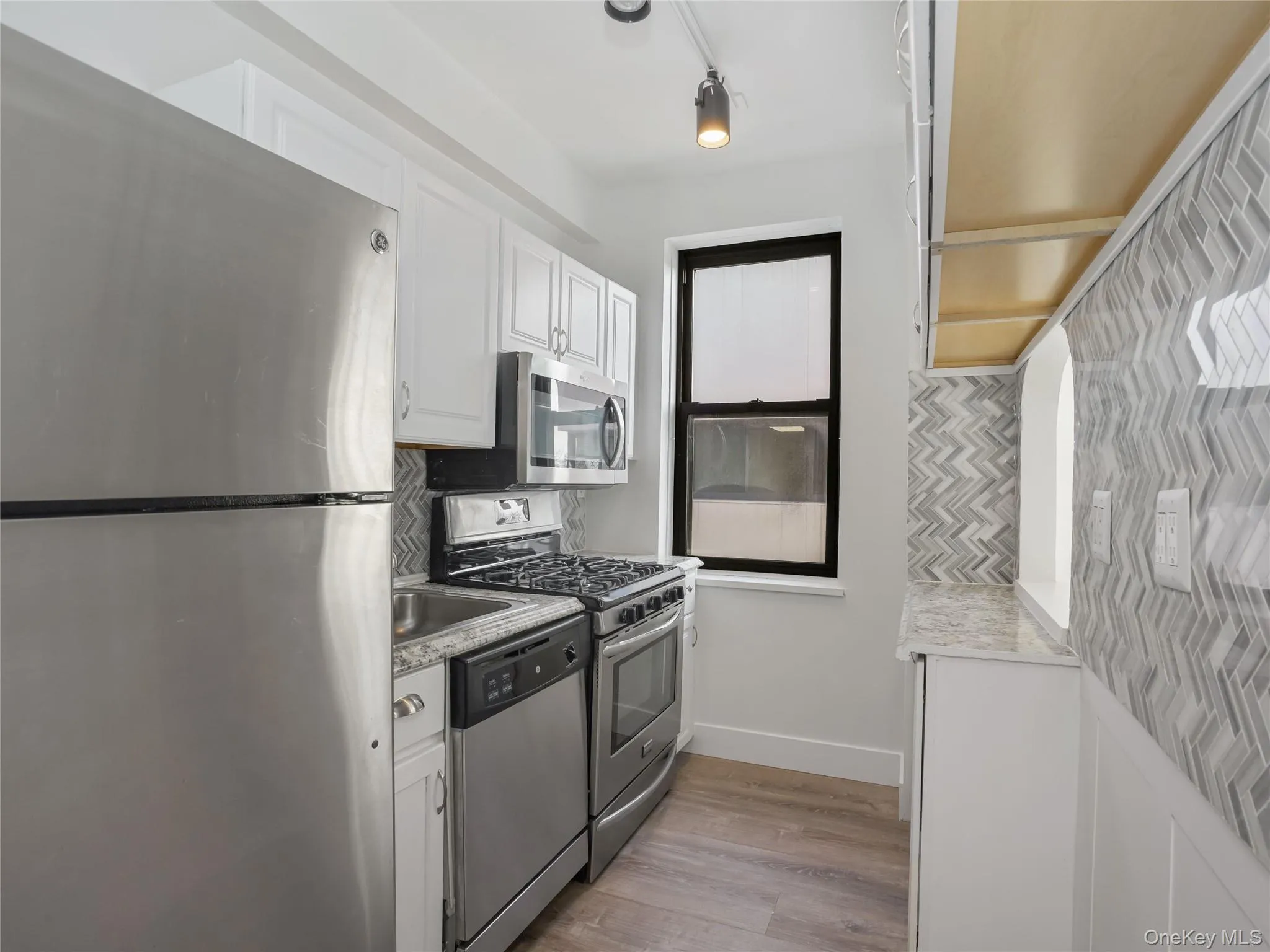 Kitchen featuring stainless steel appliances and white cabinetry Kitchen featuring stainless steel appliances and white cabinetry