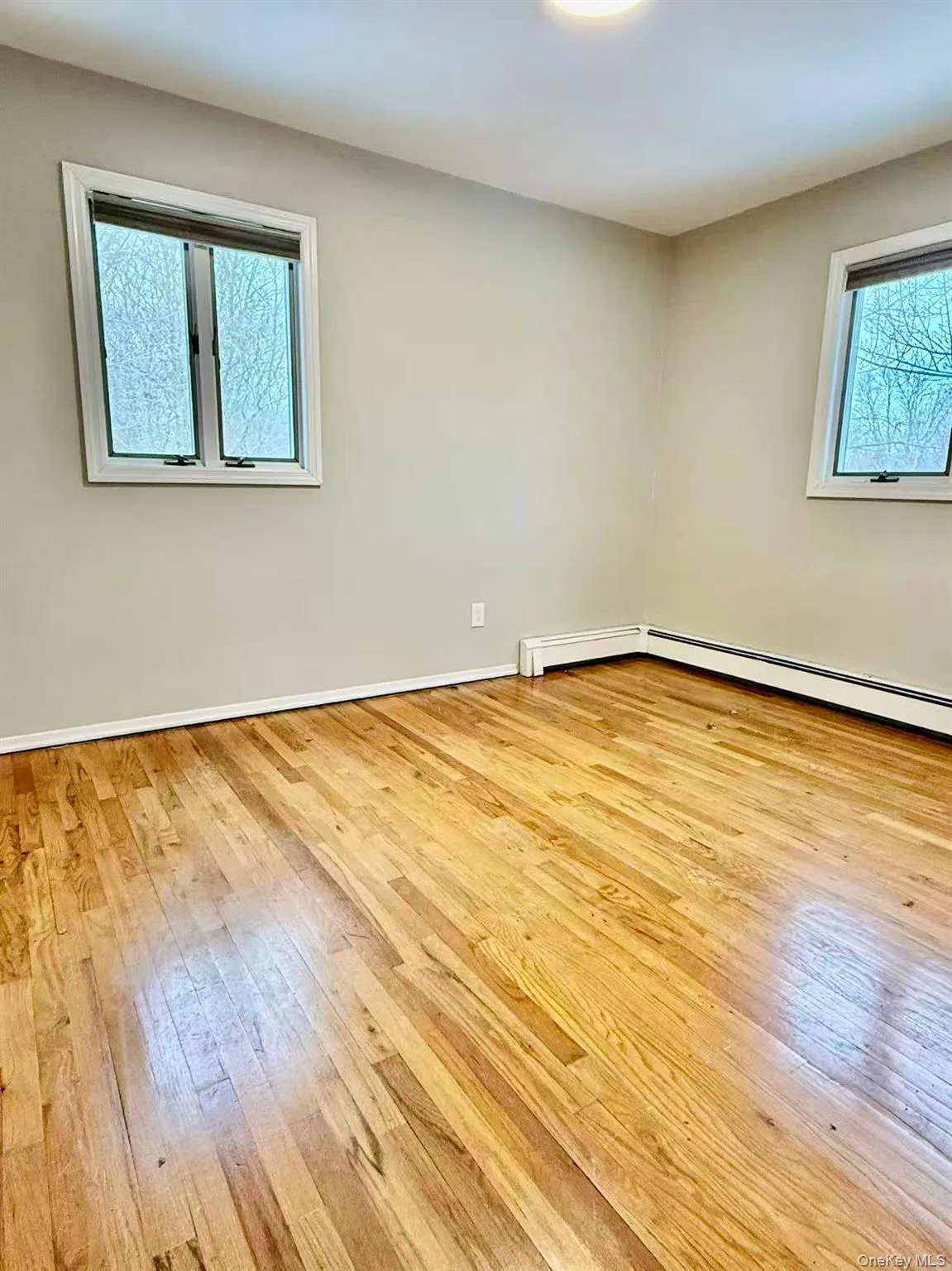 Empty room with healthy amount of natural light and light wood-style floors Empty room with healthy amount of natural light and light wood-style floors