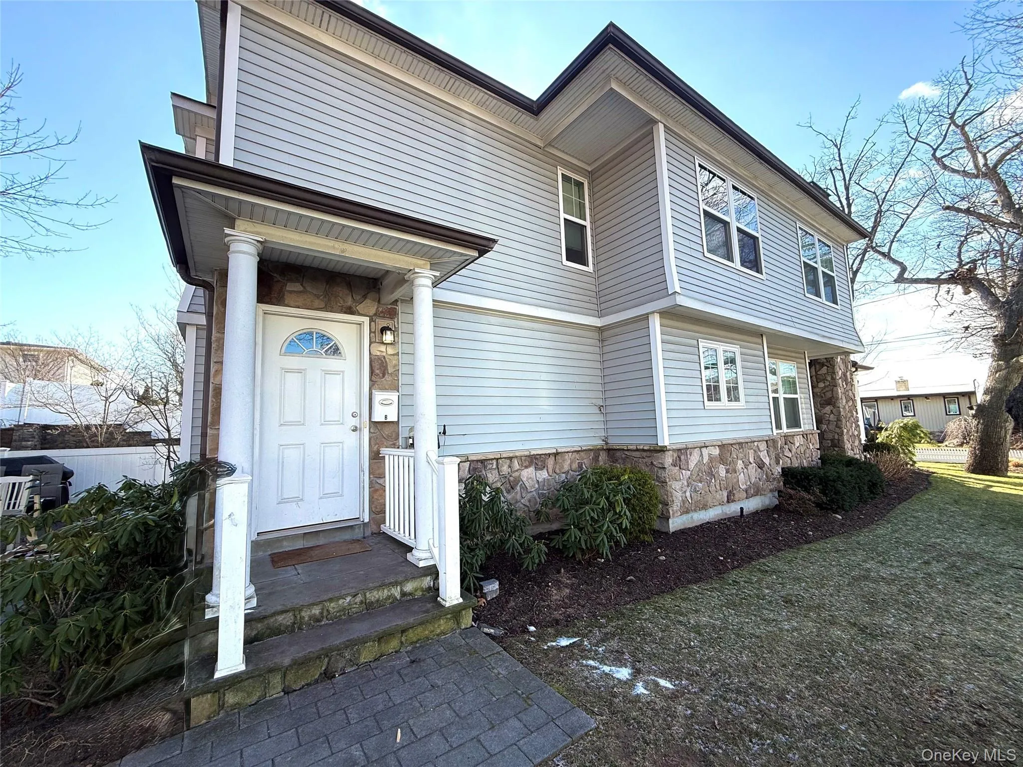 View of front of home featuring stone siding and a front lawn View of front of home featuring stone siding and a front lawn