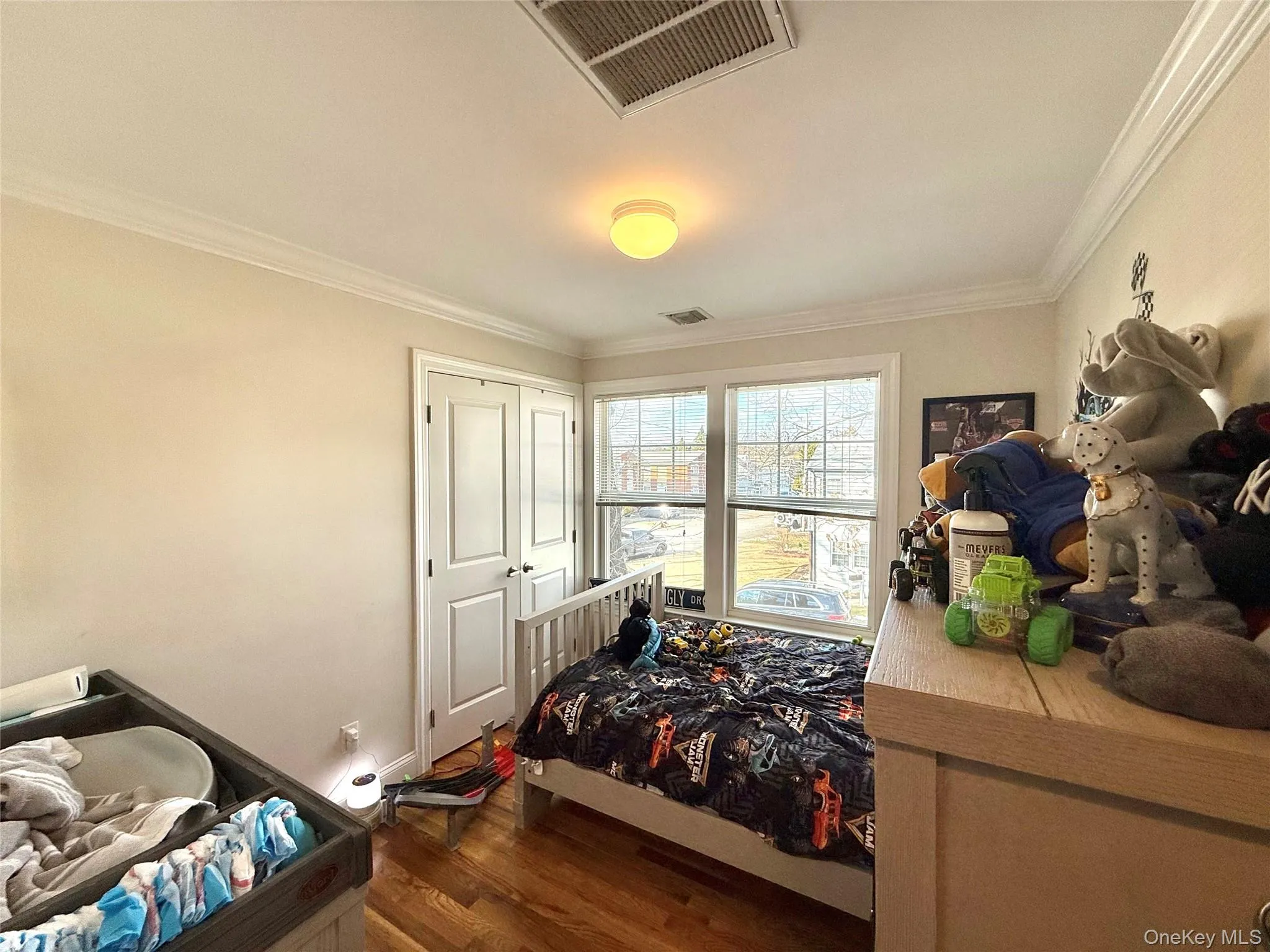 Bedroom featuring crown molding and dark wood-style flooring Bedroom featuring crown molding and dark wood-style flooring
