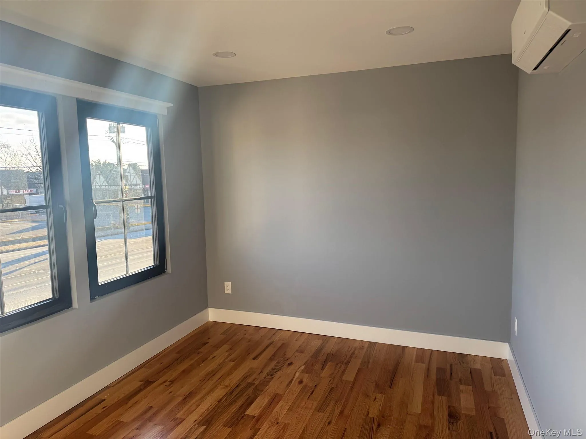 Spare room featuring wood finished floors and a wall mounted air conditioner Spare room featuring wood finished floors and a wall mounted air conditioner
