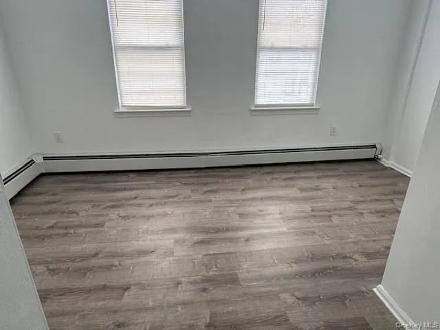 Spare room with a baseboard heating unit, wood finished floors, and healthy amount of natural light Spare room with a baseboard heating unit, wood finished floors, and healthy amount of natural light