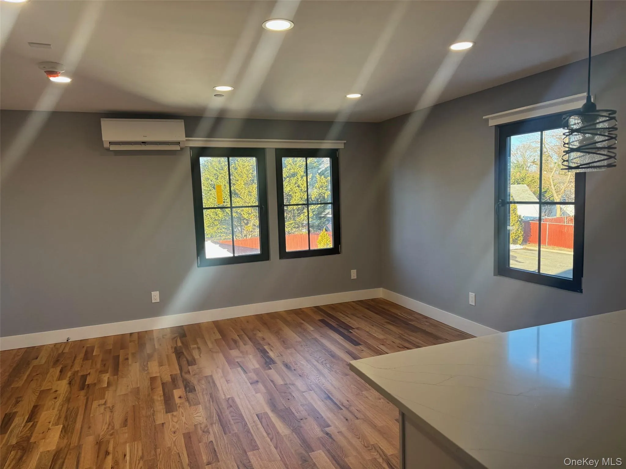 Unfurnished dining area featuring recessed lighting, wood finished floors, and a wall mounted air conditioner Unfurnished dining area featuring recessed lighting, wood finished floors, and a wall mounted air conditioner