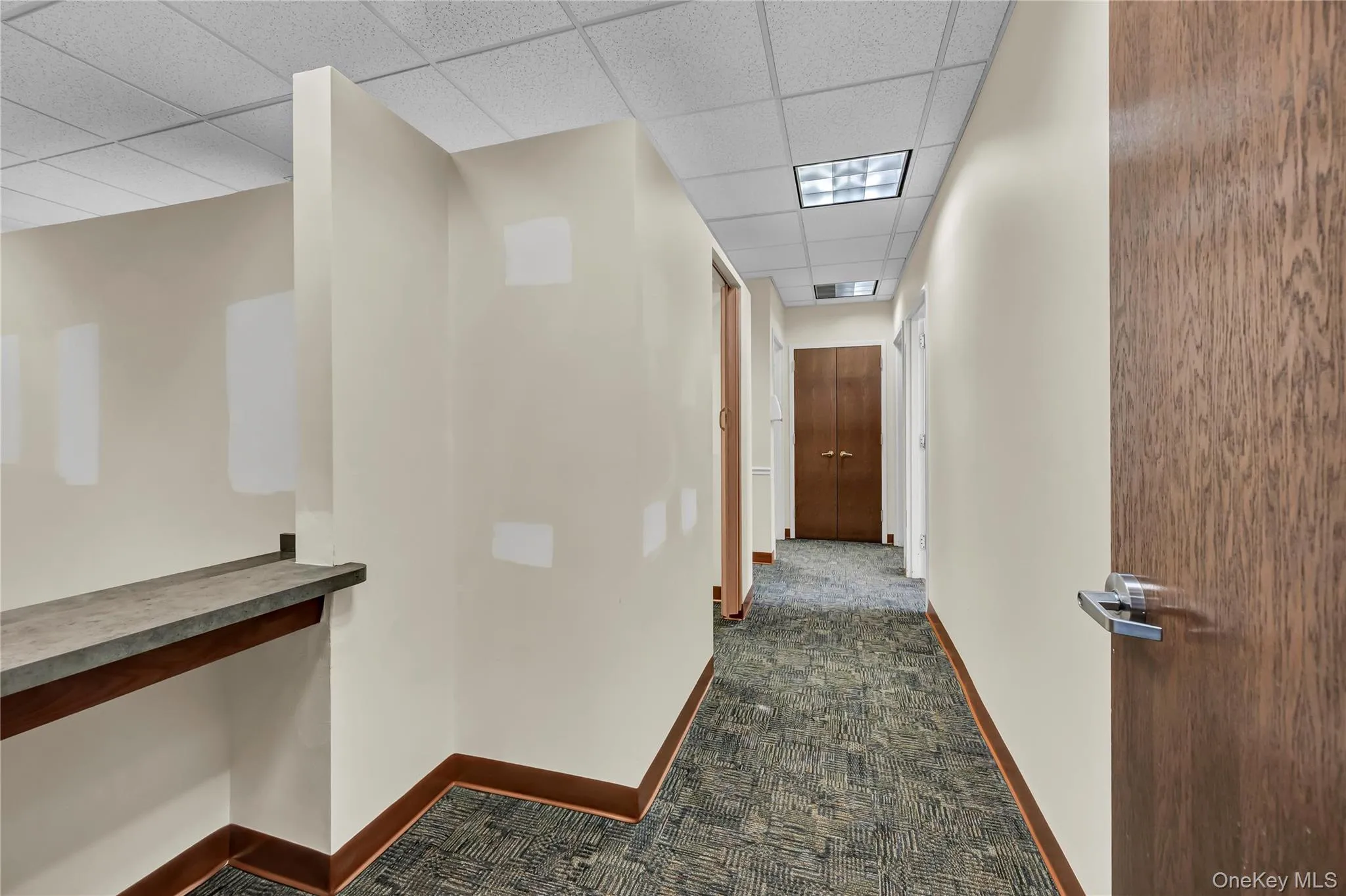 Hall with dark carpet and a paneled ceiling Hall with dark carpet and a paneled ceiling