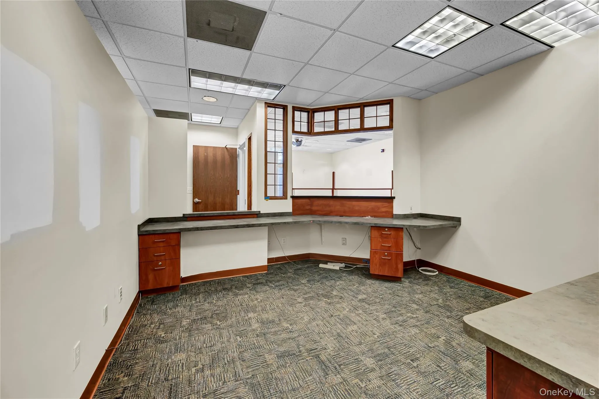 Unfurnished office featuring built in desk and a drop ceiling Unfurnished office featuring built in desk and a drop ceiling