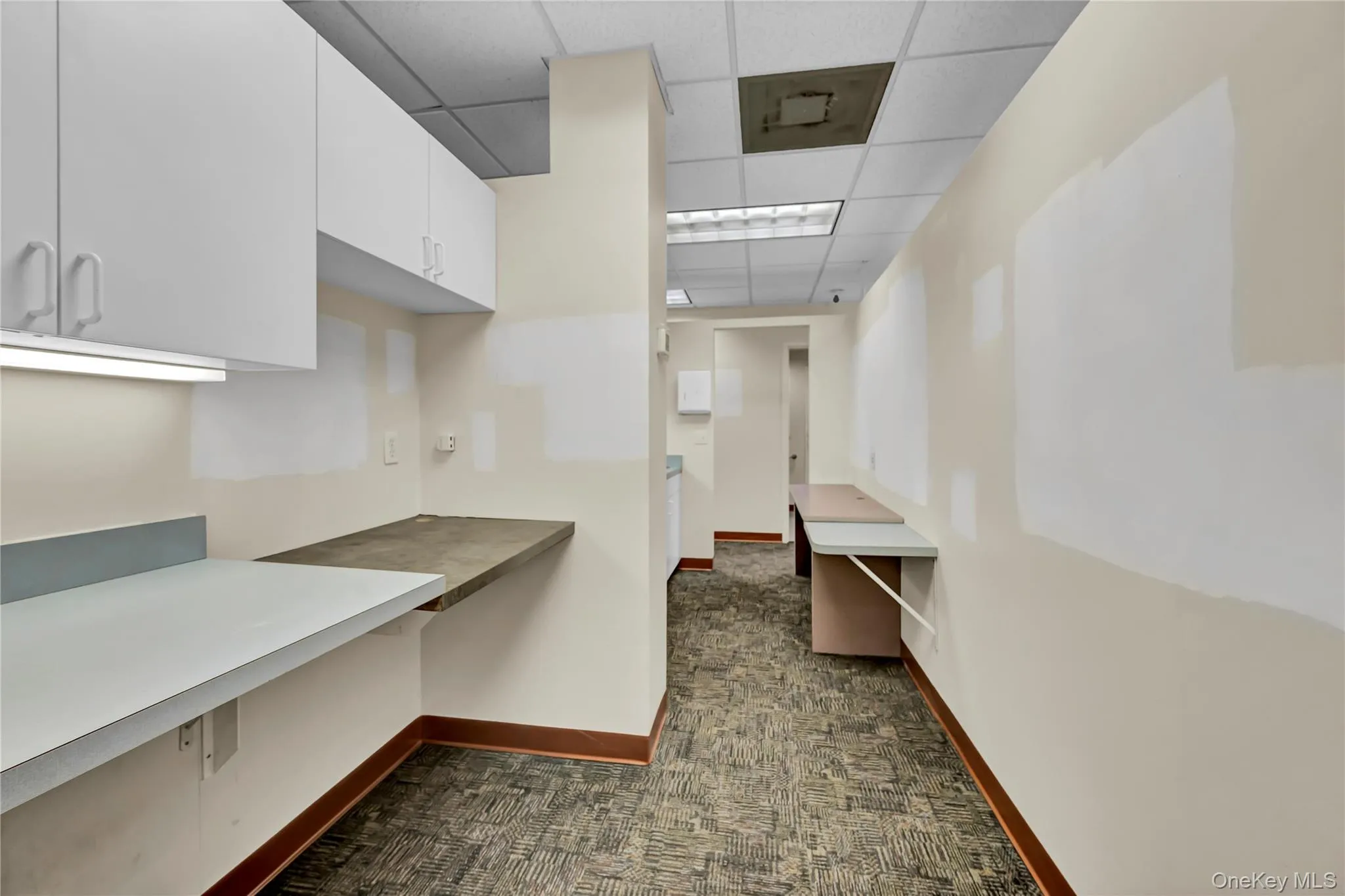 Kitchen featuring light countertops, white cabinets, and a paneled ceiling Kitchen featuring light countertops, white cabinets, and a paneled ceiling