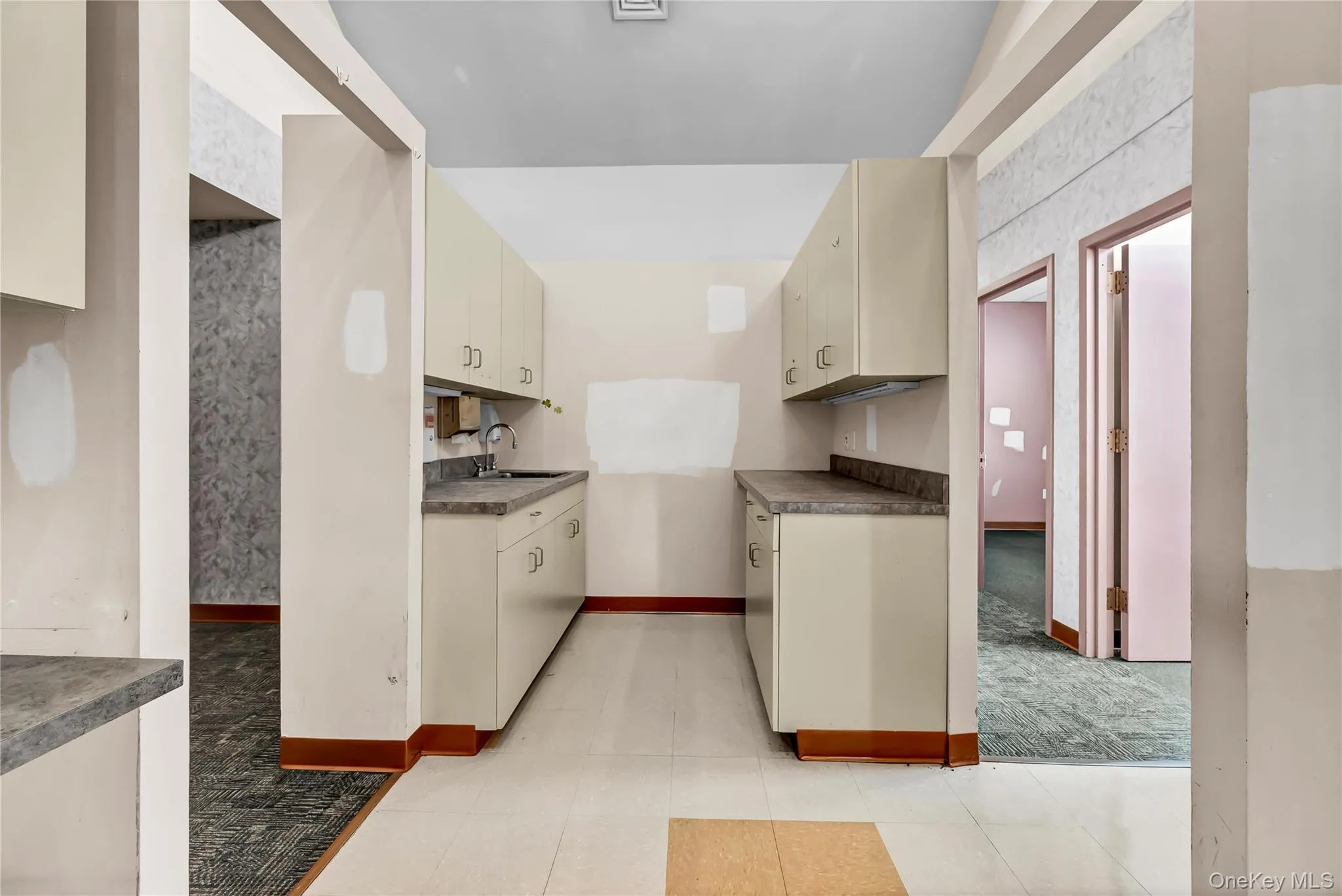 Kitchen featuring cream cabinets, dark countertops, and light carpet Kitchen featuring cream cabinets, dark countertops, and light carpet
