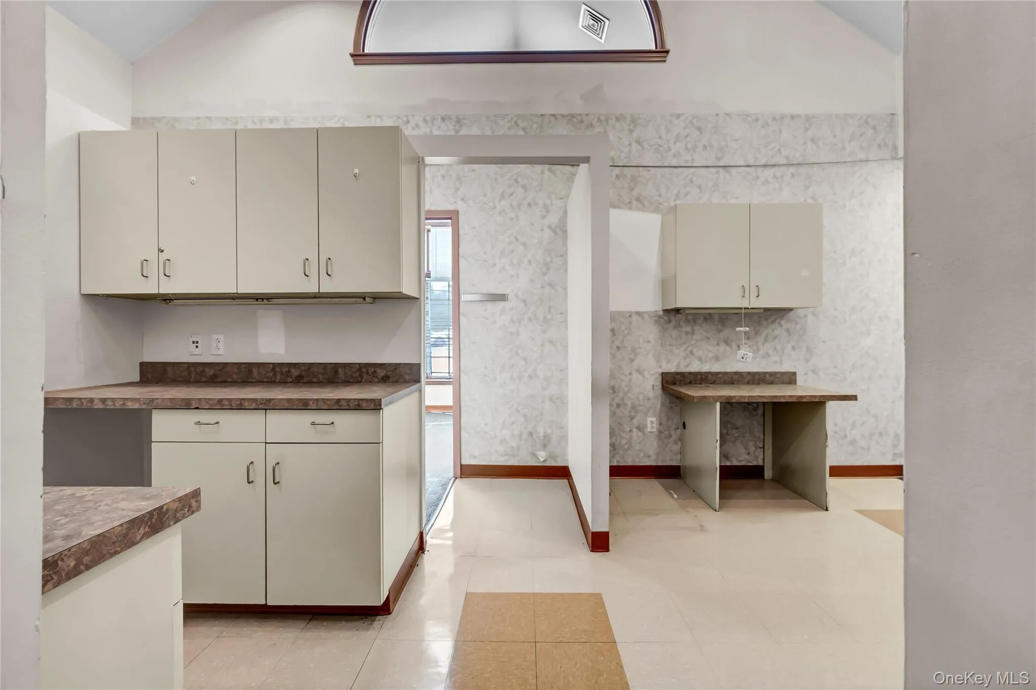 Kitchen featuring vaulted ceiling, dark countertops, and light tile patterned flooring Kitchen featuring vaulted ceiling, dark countertops, and light tile patterned flooring
