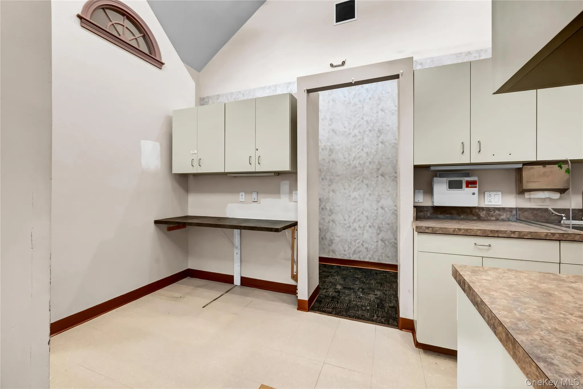 Kitchen featuring vaulted ceiling and baseboards Kitchen featuring vaulted ceiling and baseboards
