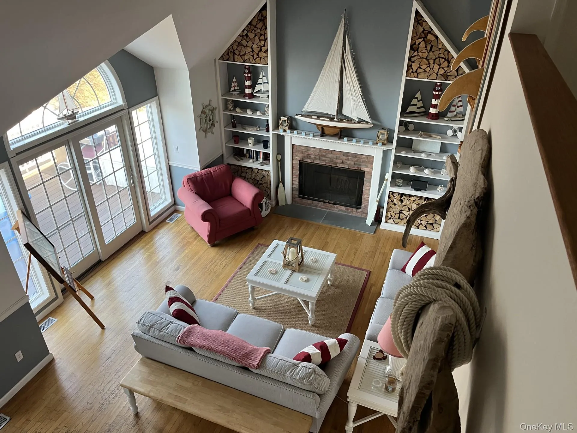 Living room featuring a fireplace, light wood-style floors, high vaulted ceiling, and built in features Living room featuring a fireplace, light wood-style floors, high vaulted ceiling, and built in features