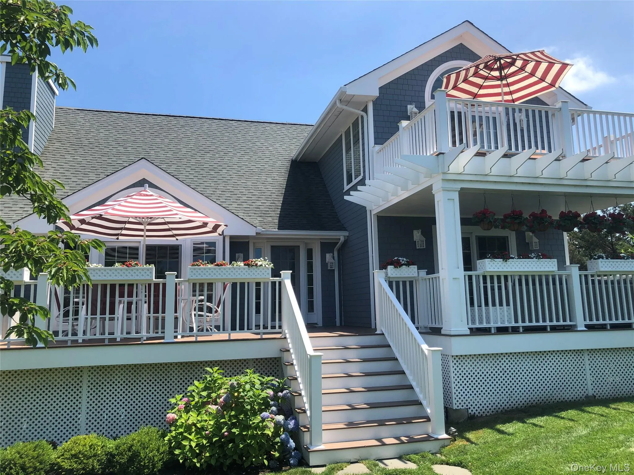 View of front of home with a shingled roof, a wooden deck, and stairway View of front of home with a shingled roof, a wooden deck, and stairway