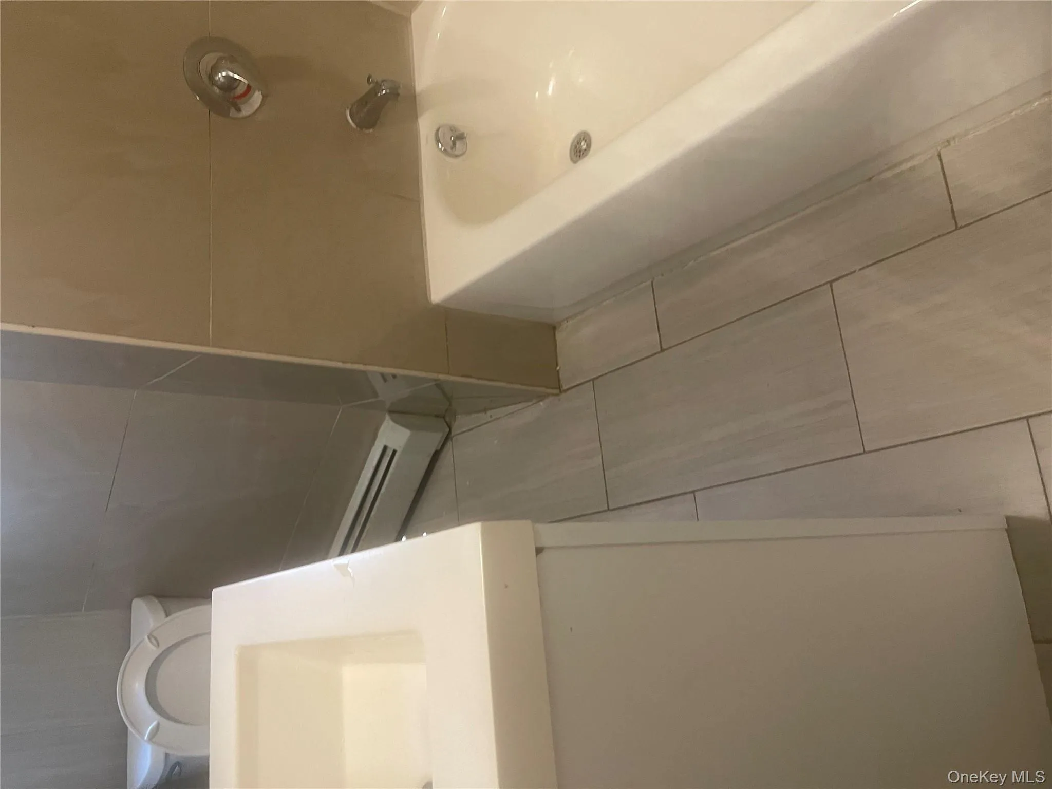 Bathroom with baseboard heating, vanity, light tile patterned floors, and tile walls Bathroom with baseboard heating, vanity, light tile patterned floors, and tile walls